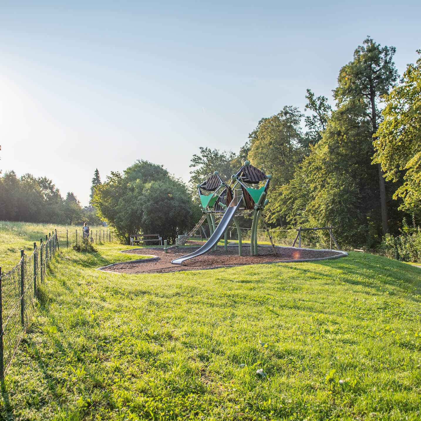 Spielplatz mit Rutsche und Klettergerüst am Holzweg auf dem Rosenhain bei Sonnenaufgang.