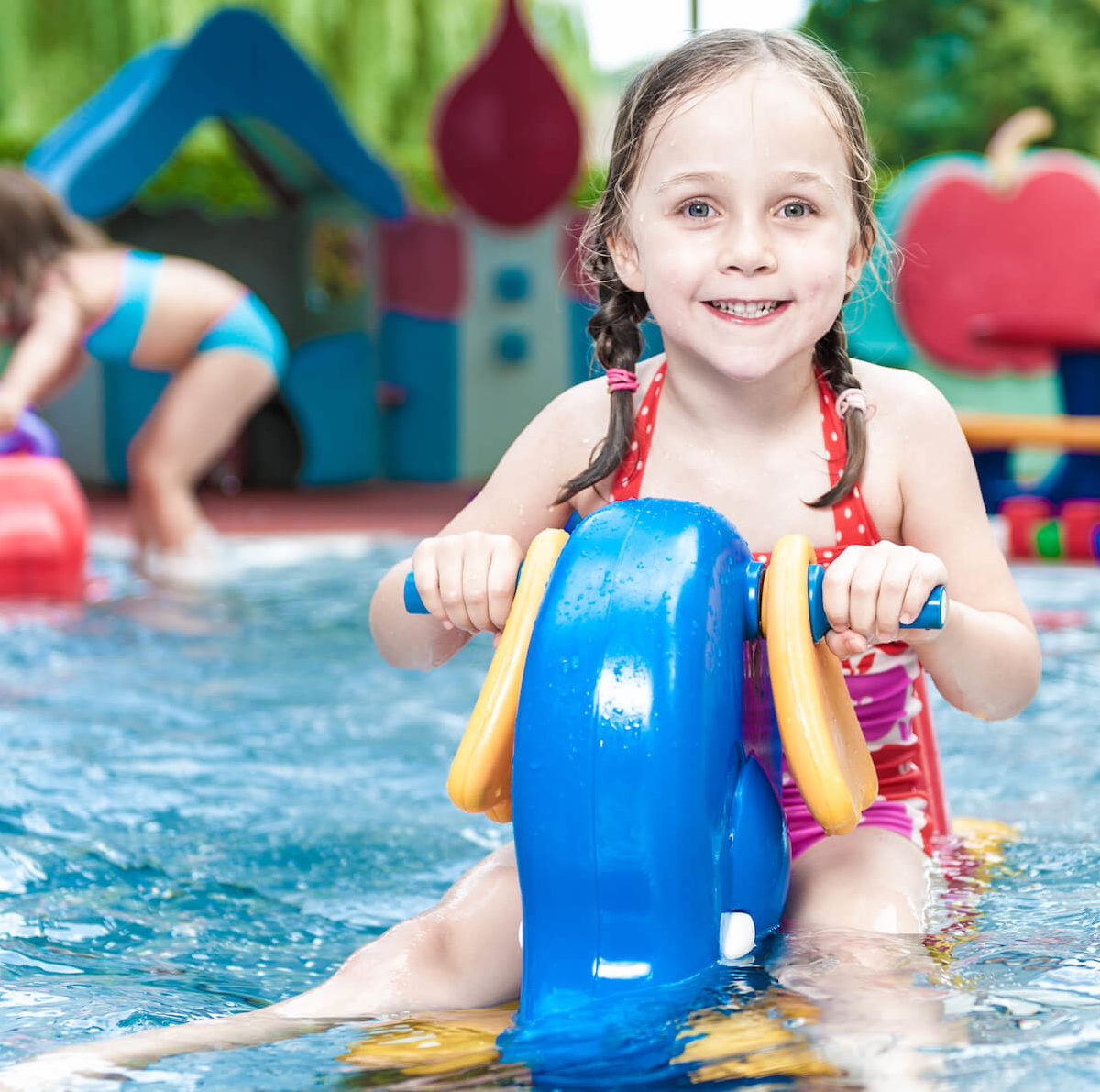 Ein lachendes Mädchen wippt im Babybecken des Stukitzbades auf einem Wasserspielzeug.