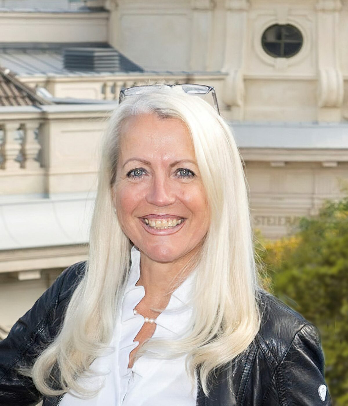 Headshot of Isabella Slivniker, smiling with blonde hair. She is wearing glasses on top of her head.