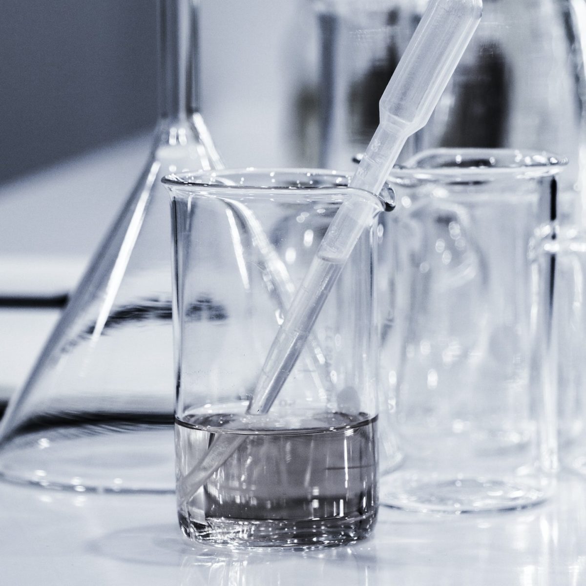 Plastik-Pipette steckt in halbvollem Glas. Im Hintergrund leeres Glas und leere Wasserkaraffe.