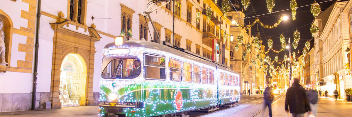 Festlich beleuchtete Adventbim fährt abends durch weihnachtlich beleuchtete Herrengasse.