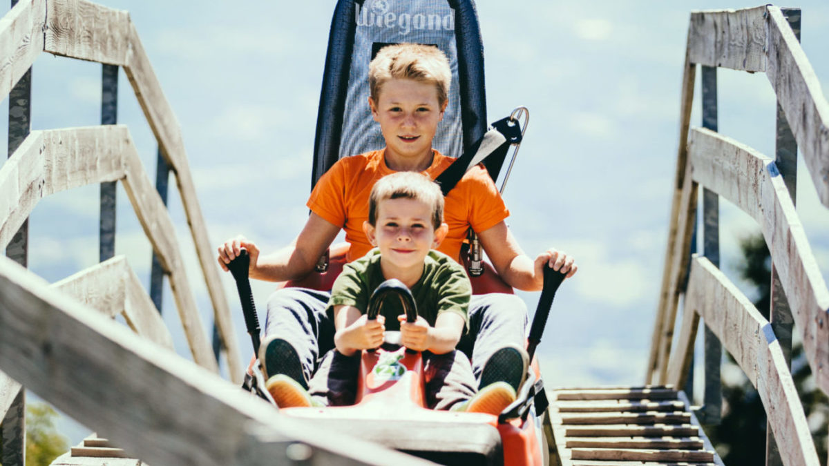 Zwei junge Buben fahren bei sonnigem Wetter mit dem Hexenexpress am Schöckl.