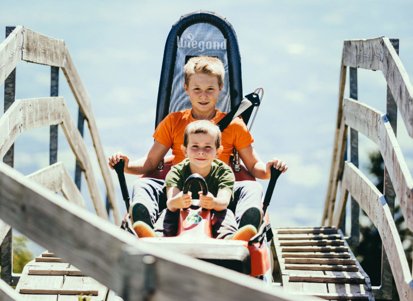 Zwei junge Buben fahren bei sonnigem Wetter mit dem Hexenexpress am Schöckl.