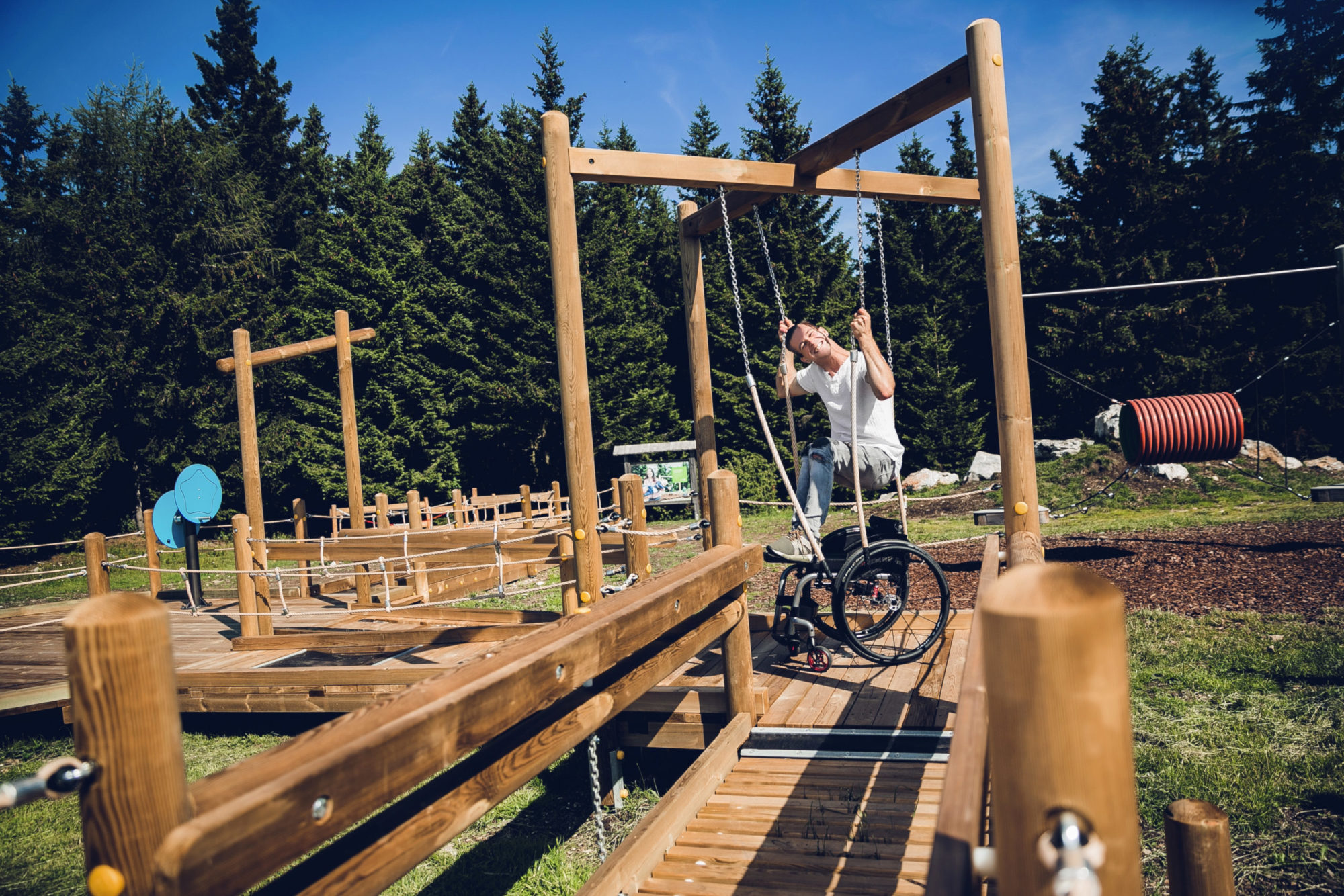 Rollstuhlfahrer zieht sich mit Seilen auf dem Motorikparkour am Schöckl aus seinem Rollstuhl.