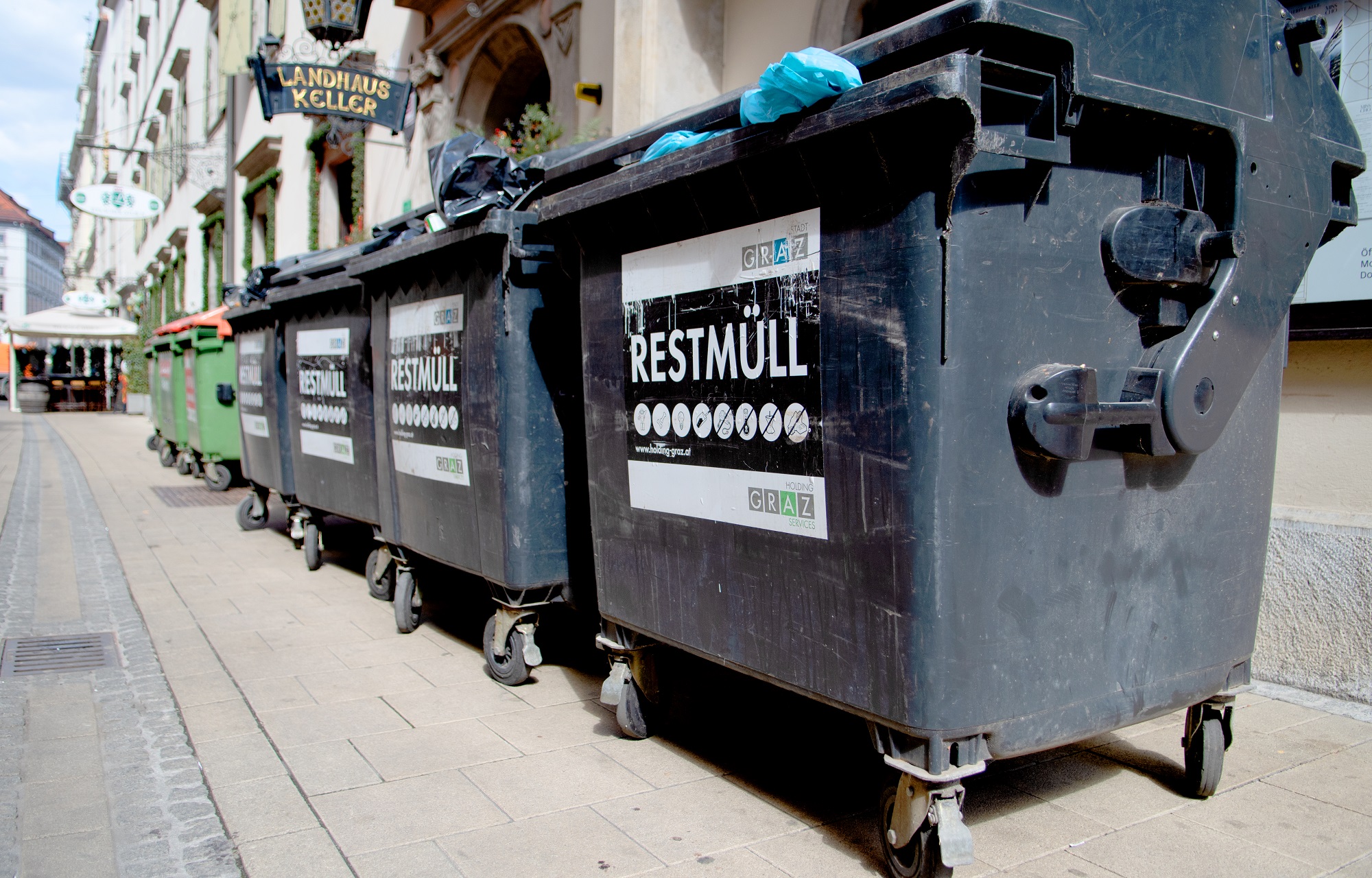 Reihe von schwarzen Müllcontainern mit Aufschrift „Restmüll“ vor dem "Landhauskeller".