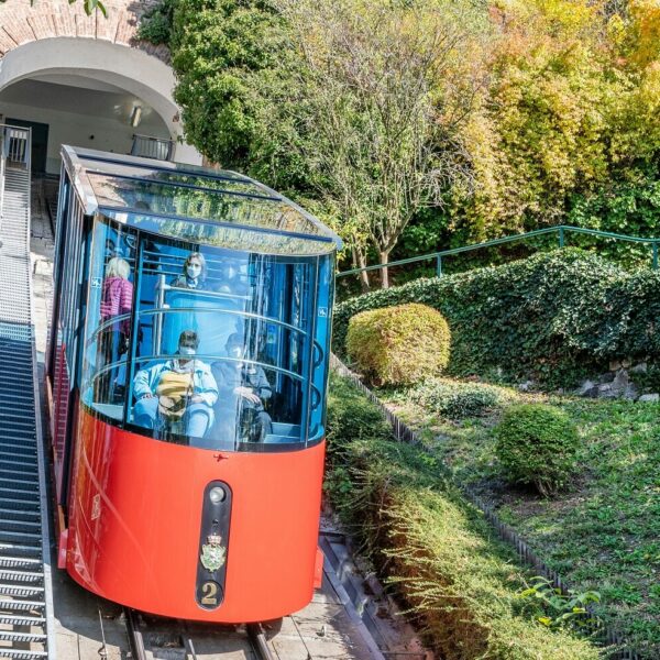 A red Schlossbergbahn funicular car, labeled "2", leaves the mountain station in Graz, Austria.