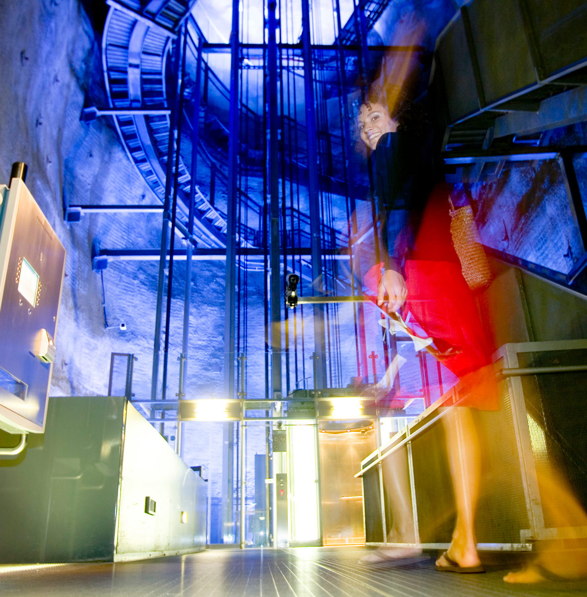 Lächelnde Frau geht auf die hell beleuchtete Talstation des Schloßbergliftes zu.