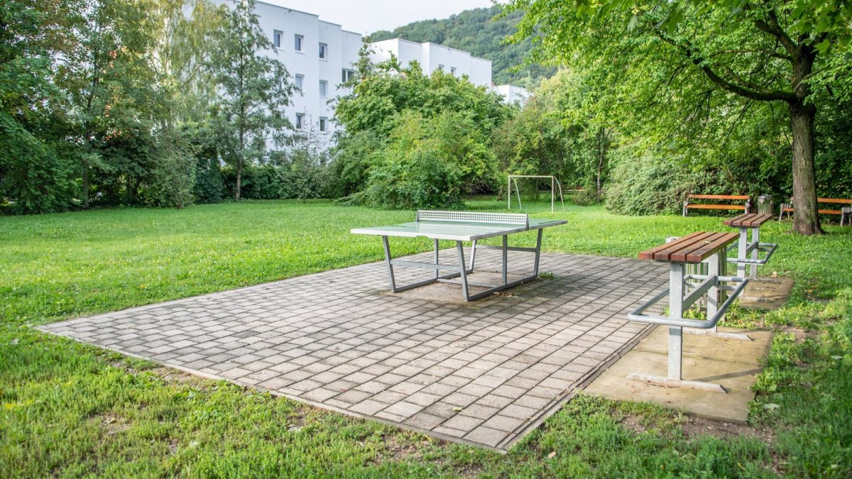 Spielplatz Dechant Binder-Anlage: Bild zeigt Wiese mit Tischtennisplatte auf gepflastertem Bereich.