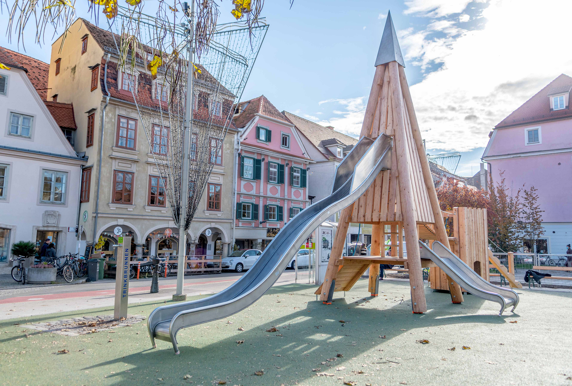 Spielplatz Kapistran-Pieller-Platz mit Klettergerüst aus Holz in Form eines Turms mit zwei Rutschen.