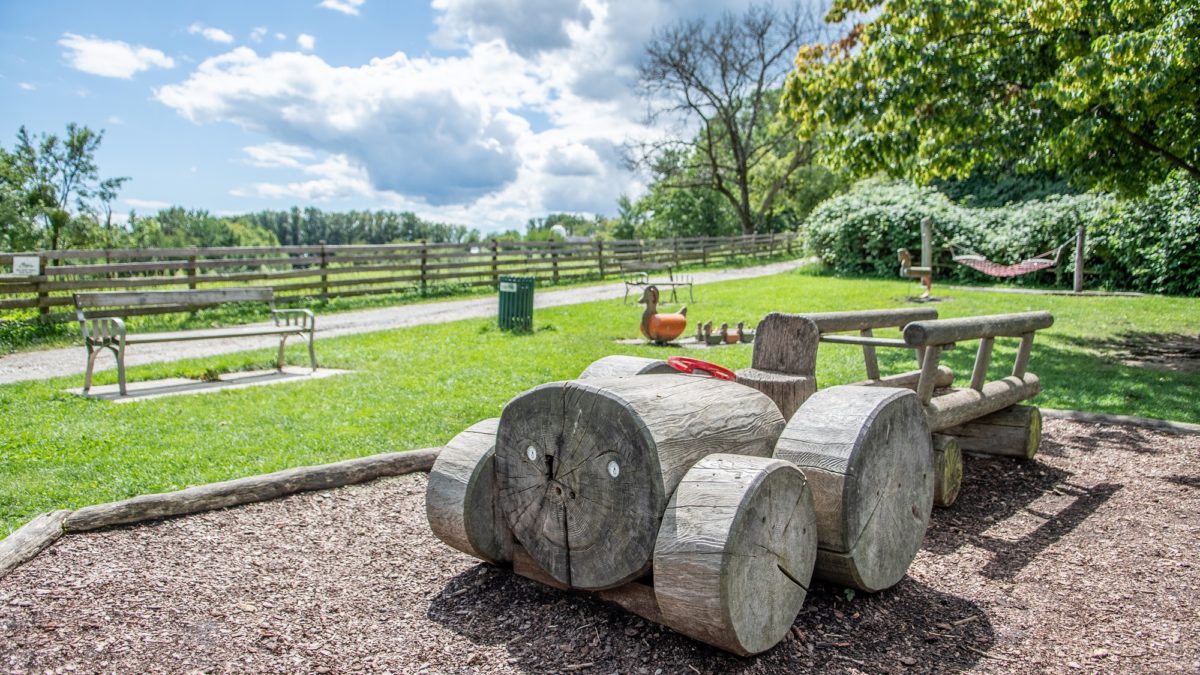 Spielplatz Lustbühel: Im Vordergrund steht eine Holzspielskulptur, die wie ein Auto gestaltet ist.