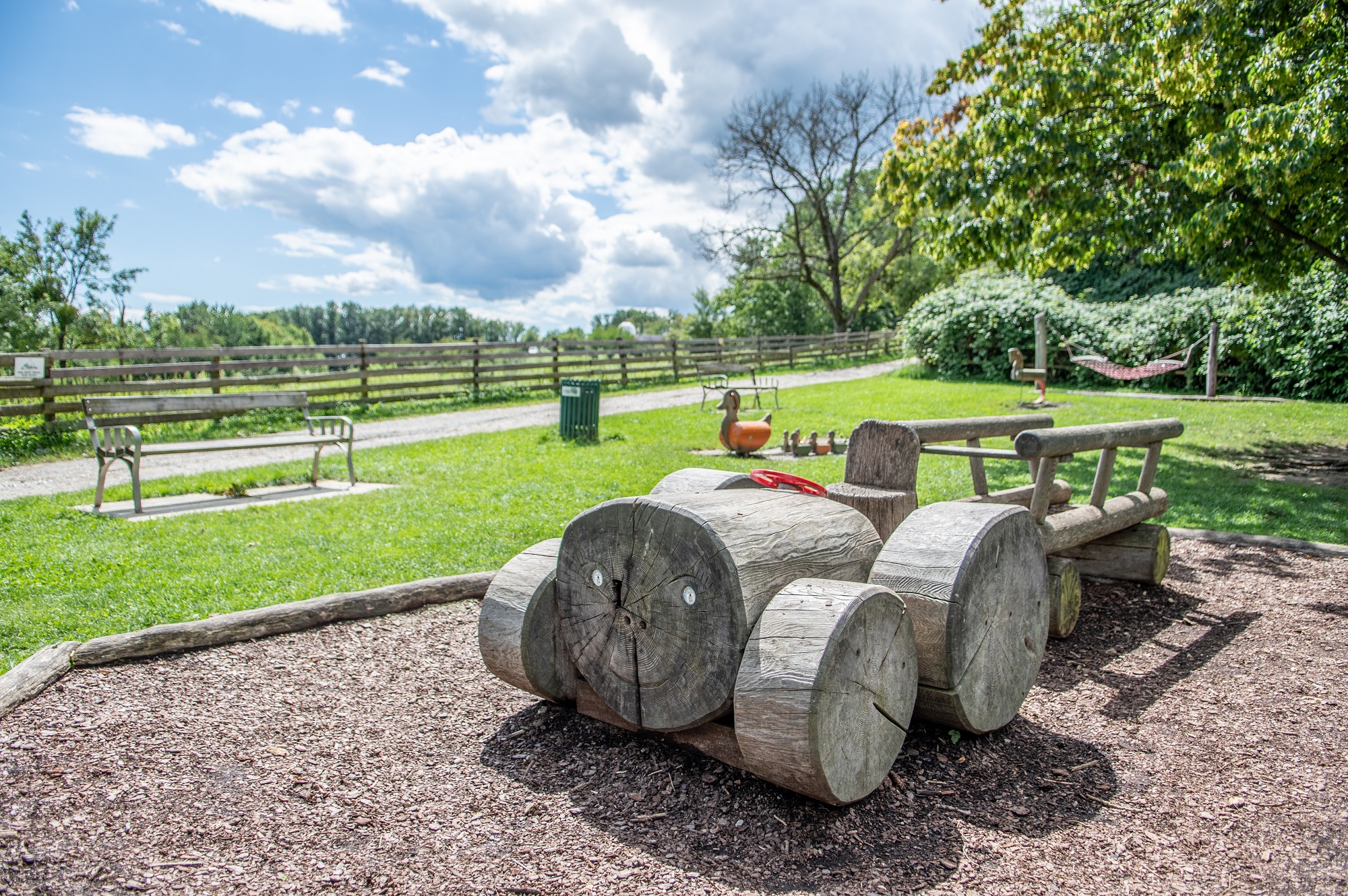 Spielplatz Lustbühel: Im Vordergrund steht eine Holzspielskulptur, die wie ein Auto gestaltet ist.