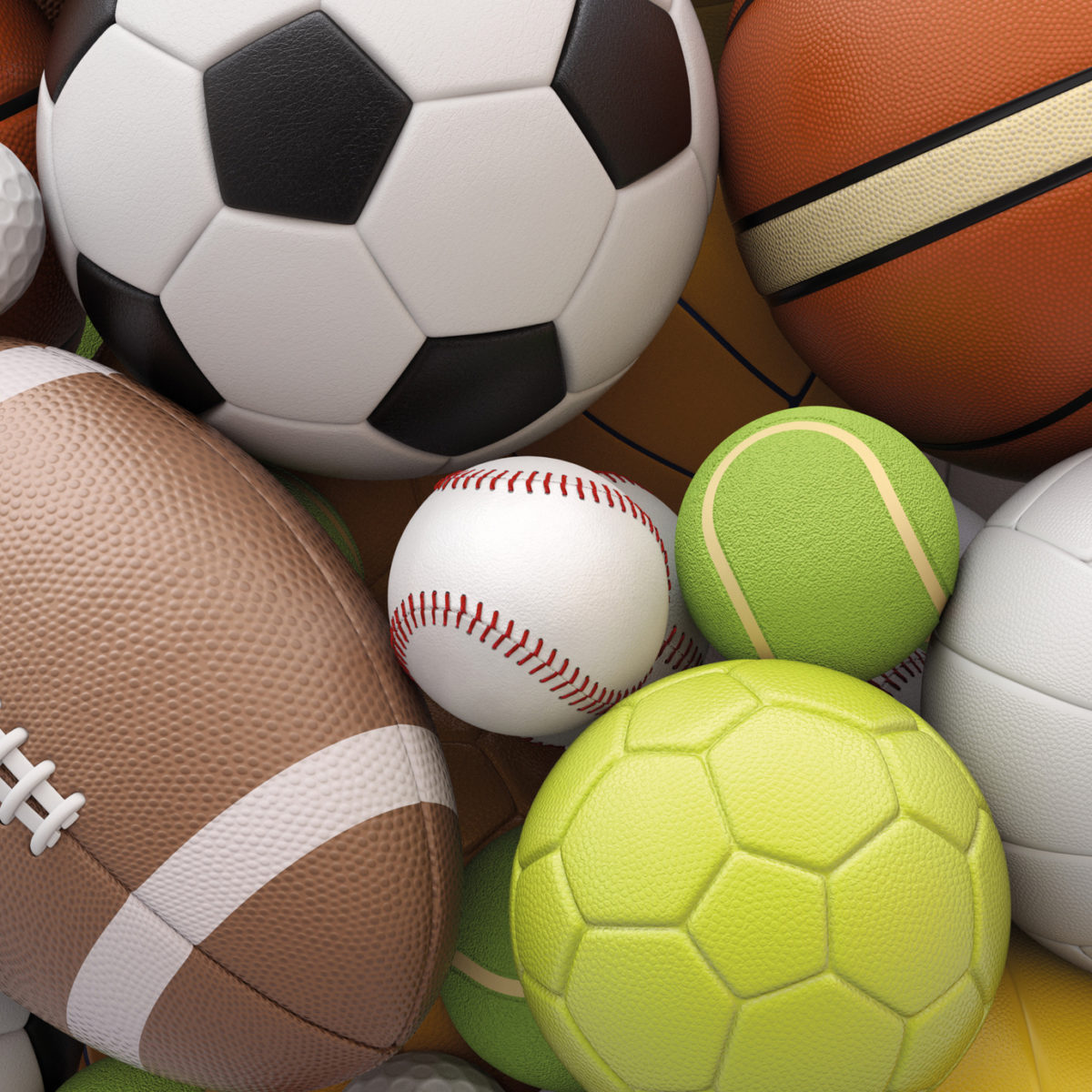 A close-up of a pile of various sports balls, including a football, basketball, soccer ball, baseball, and tennis balls.