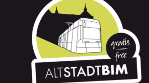 A tram in front of a building with the text "gratis - free" and "ALTSTADTBIM".