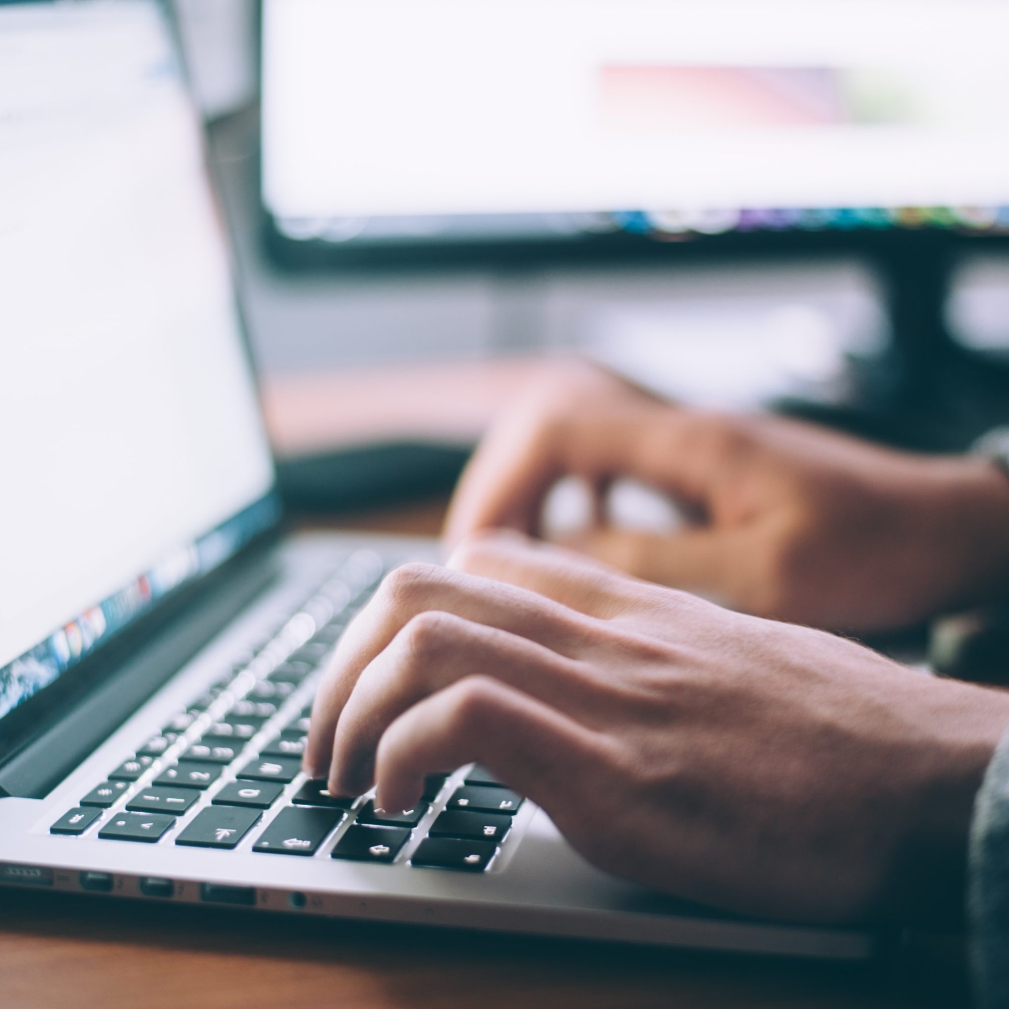 A person's hands type on a laptop keyboard.