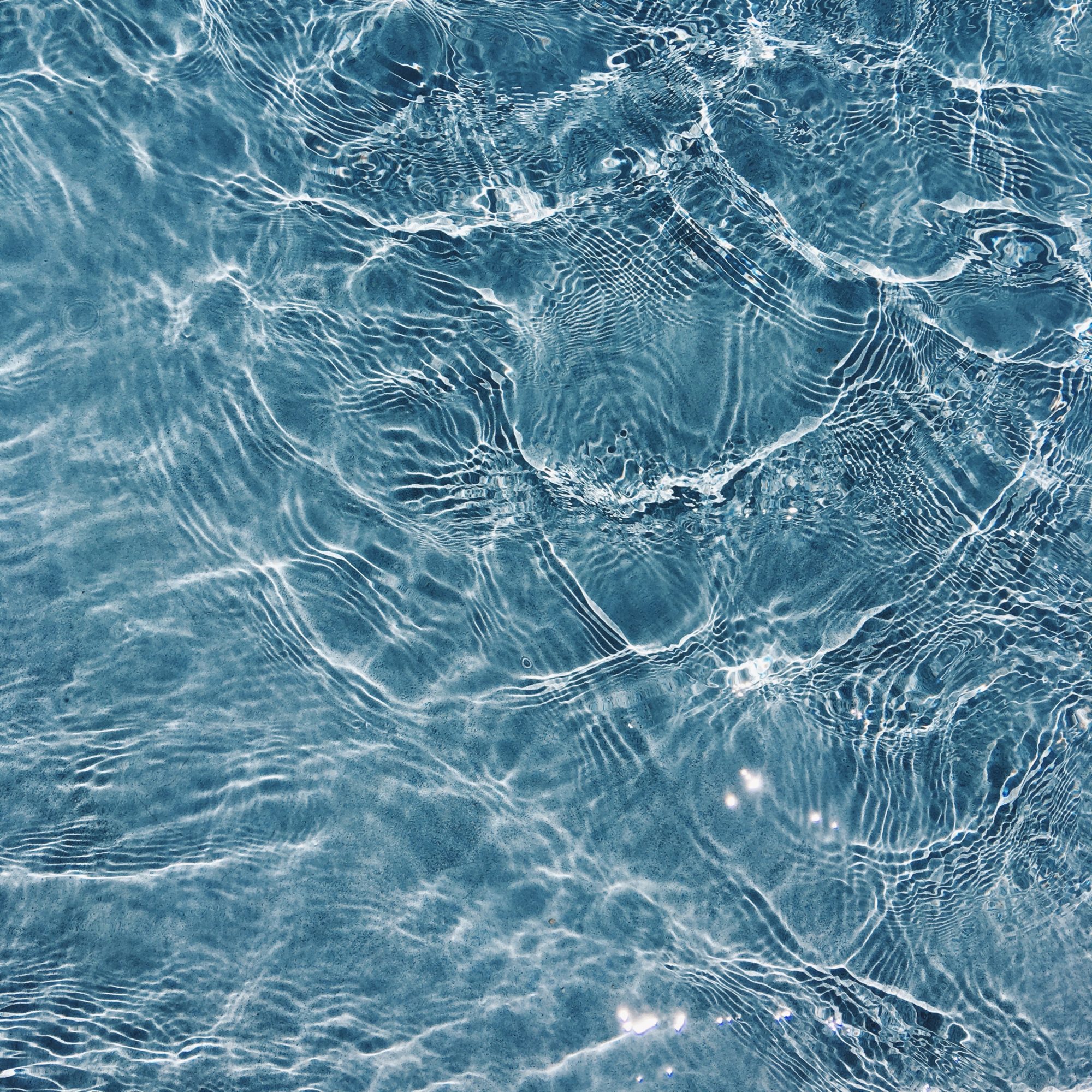 Close-up view of clear, blue water with ripples and light reflecting off the surface.