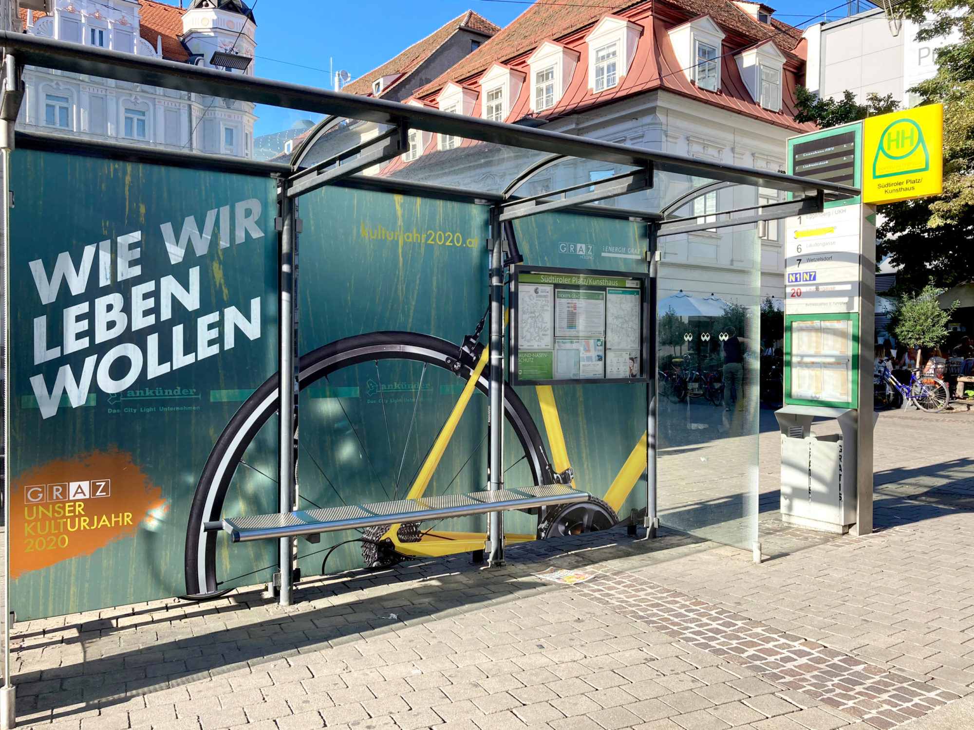 Moderne Haltestelle am Südtiroler Platz mit Glasdach und Werbeplakaten.