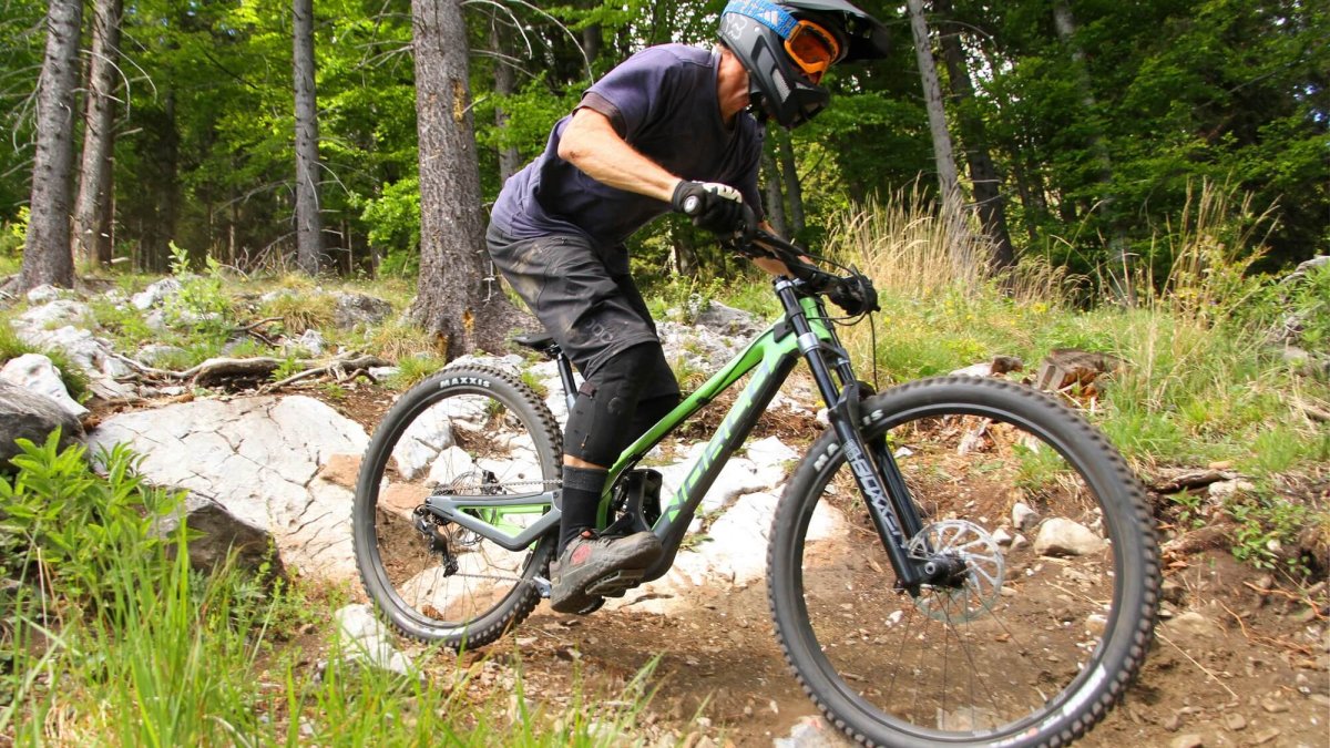Mountainbiker fährt an Waldrand steinigen Abschnitt der Schöckl Trail Area hinab