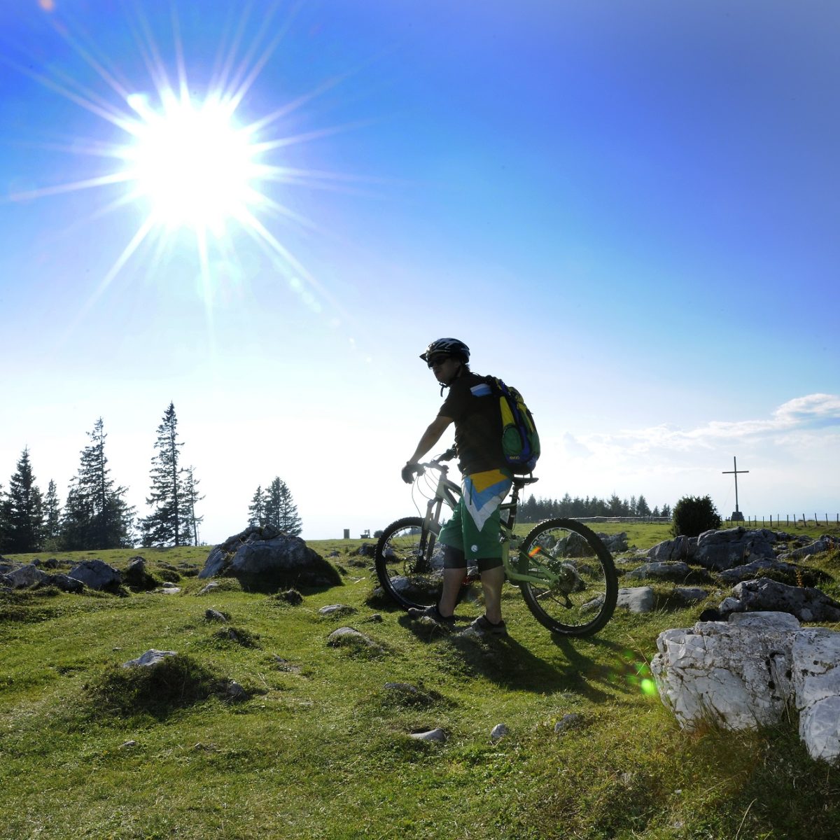 Mountainbiker steht bei strahlendem Sonnenschein am Schöckl-Plateau neben seinem Rad