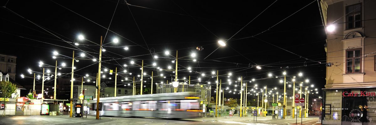 Straßenbahn fährt nachts über den leeren und beleuchteten Jakominiplatz