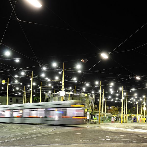 A tram passes through Jakominiplatz at night, illuminated by streetlights.