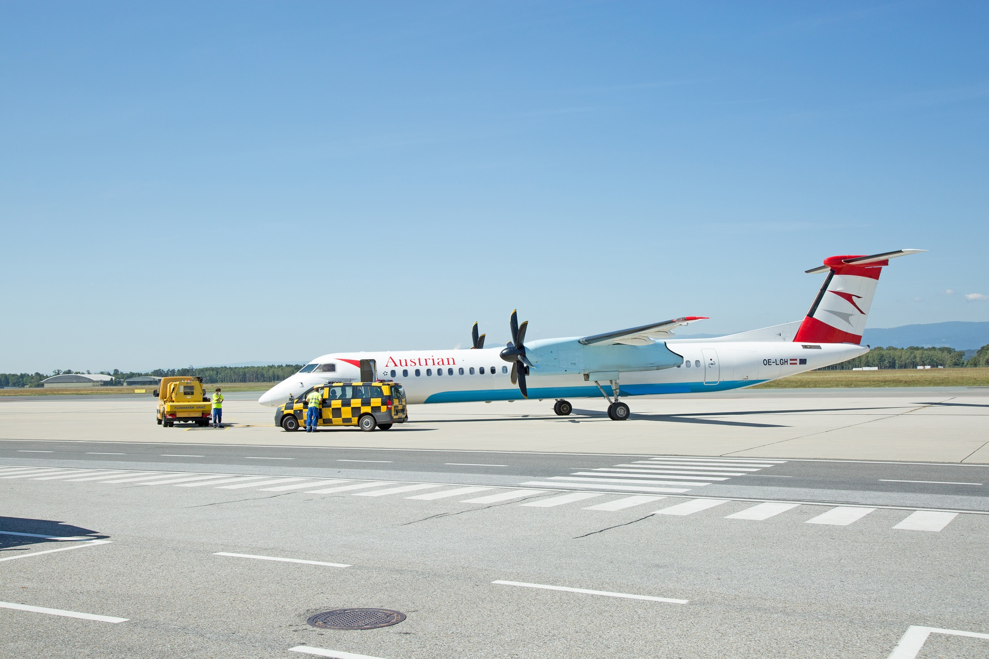Austrian-Flugzeug samt Flughafenmitarbeitern auf Start- und Landebahn am Flughafen Graz