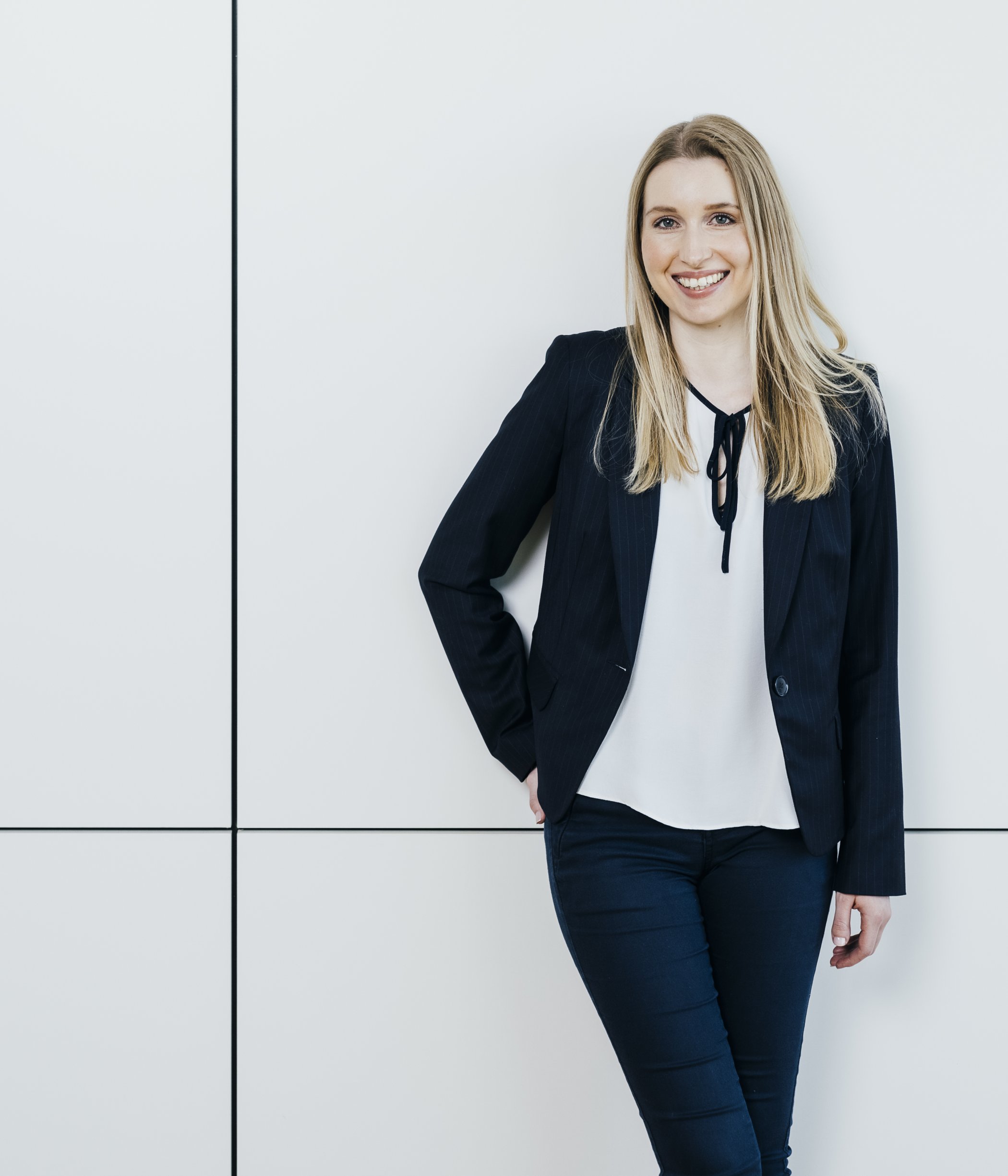 Portrait of Sara Schmidt, a woman with long blonde hair, wearing a black blazer and smiling.