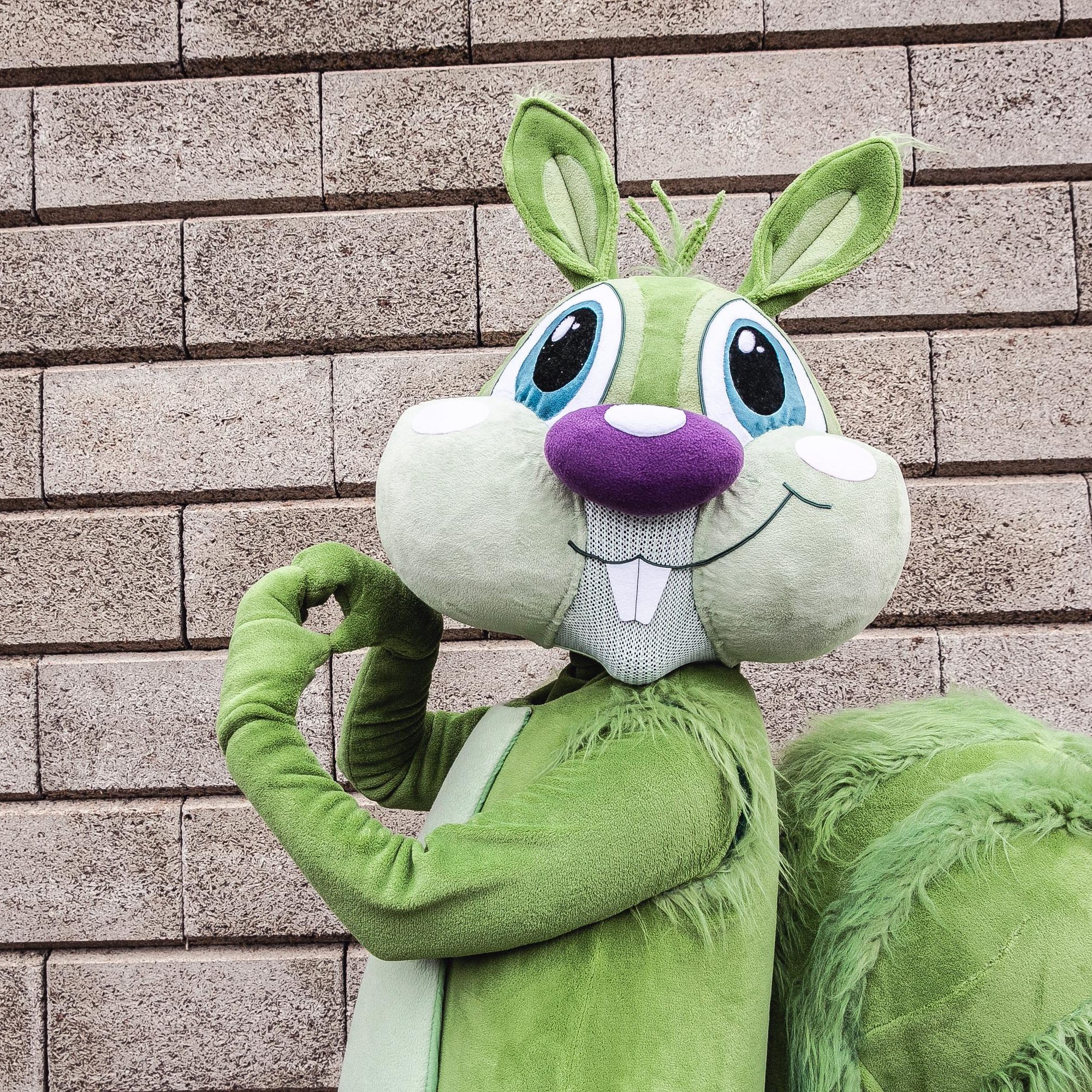 Portrait des Holding Graz-Maskottchens "Hansi" in Form eines grünen Eichhörnchens.