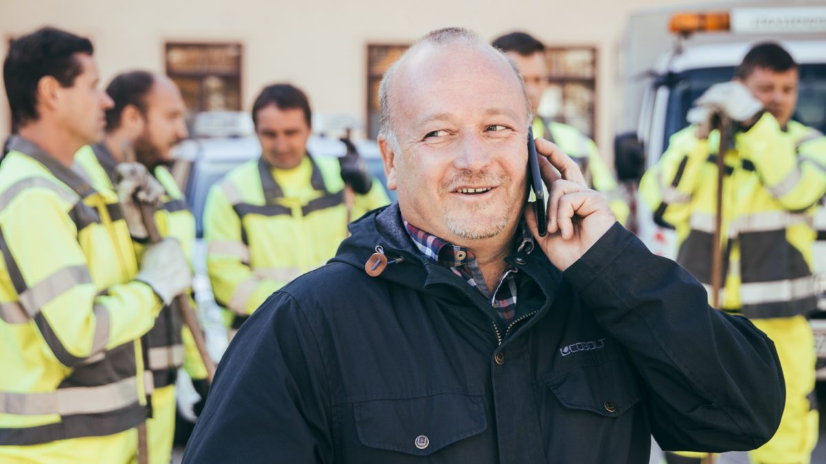 Omputzmann Thomas Hofer mit Telefon am Ohr am Karmeliterplatz, umringt von seinem Sauberkeits-Team