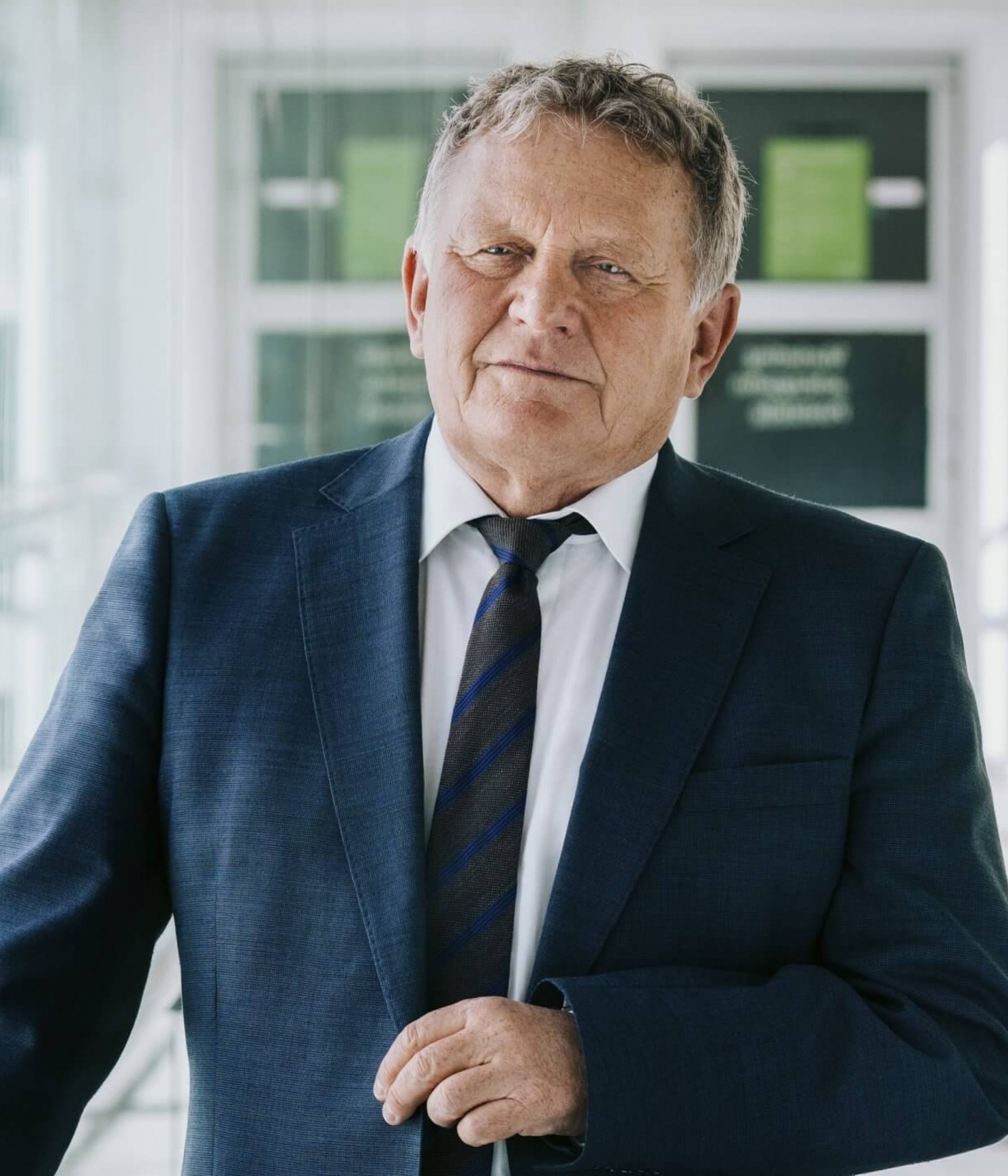 Wolfgang Malik, a man in a suit, stands in an office building hallway.
