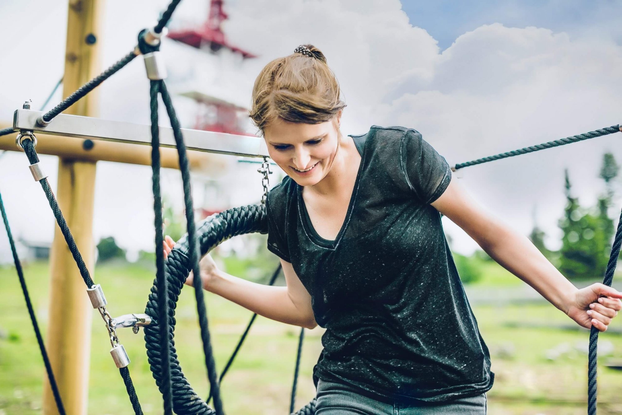 A woman smiles as she navigates a rope course at the Schöckl Motorik Park.