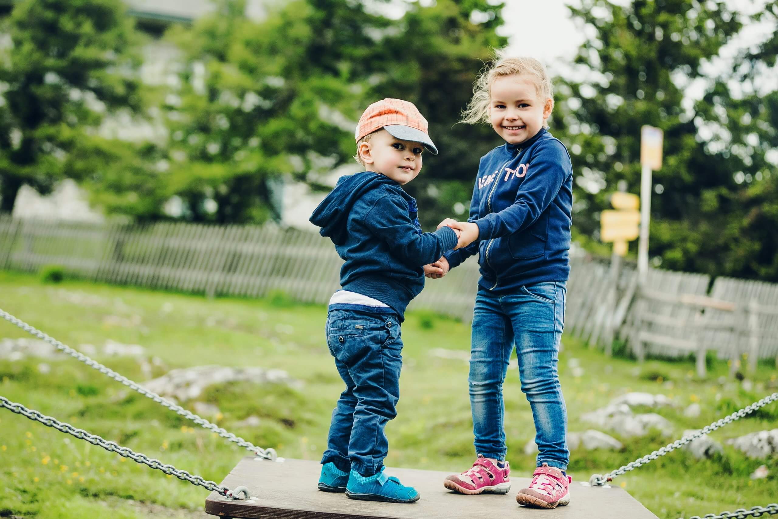 A young boy and girl hold hands on a seesaw at the Schöckl Motorikparkour.