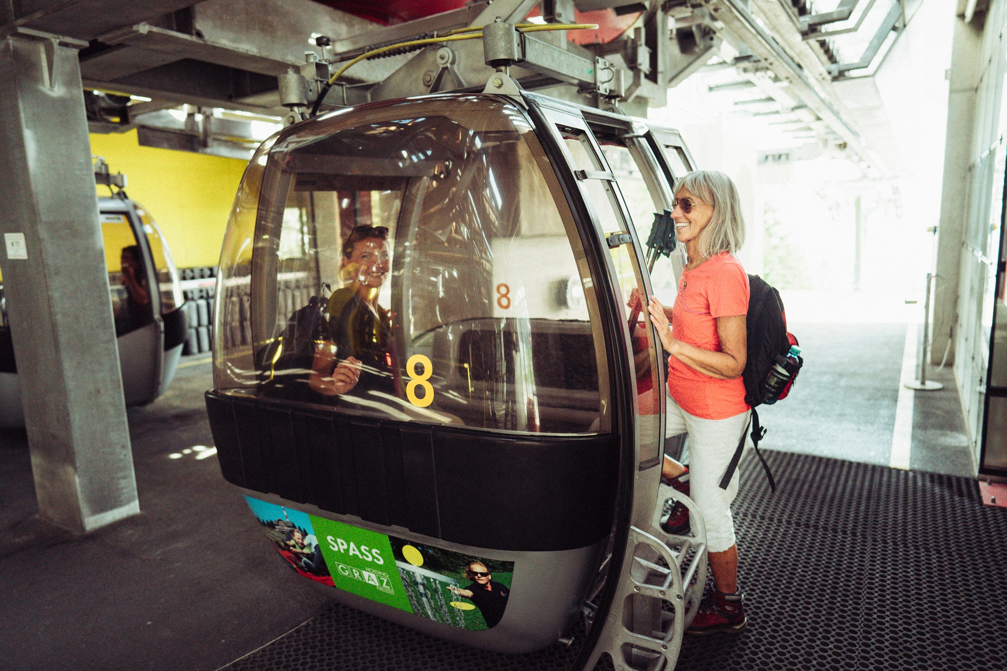 Frau mit Wanderausrüstung steigt in Talstation der Schöckl Seilbahn in Gondel ein