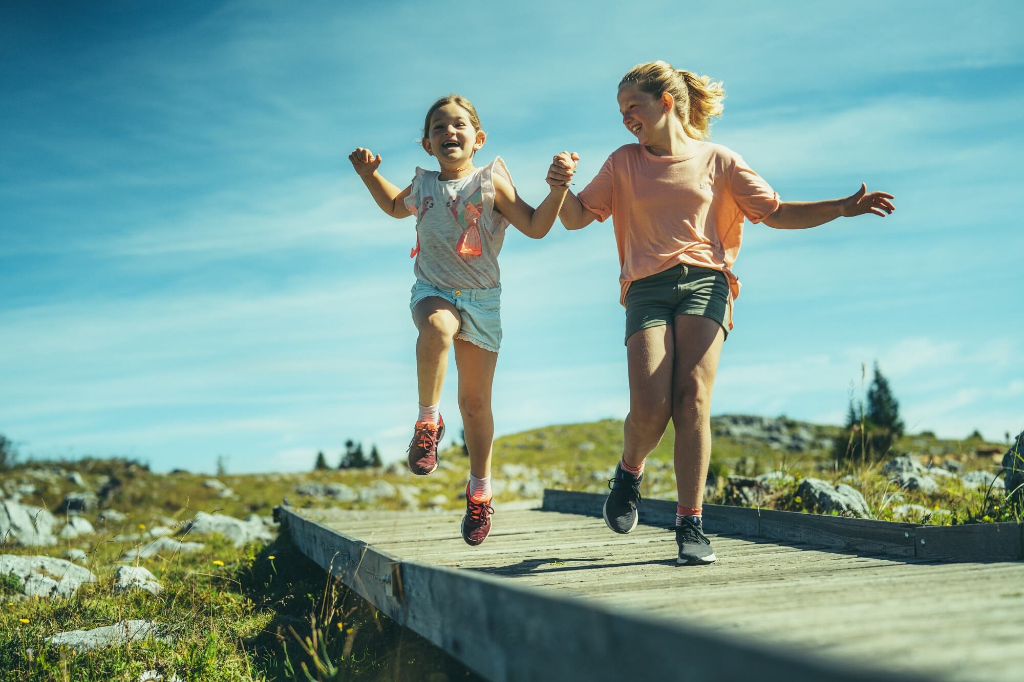 Zwei Mädchen laufen hüpfend und lachend auf dem barrierefreien Weg am Schöckl
