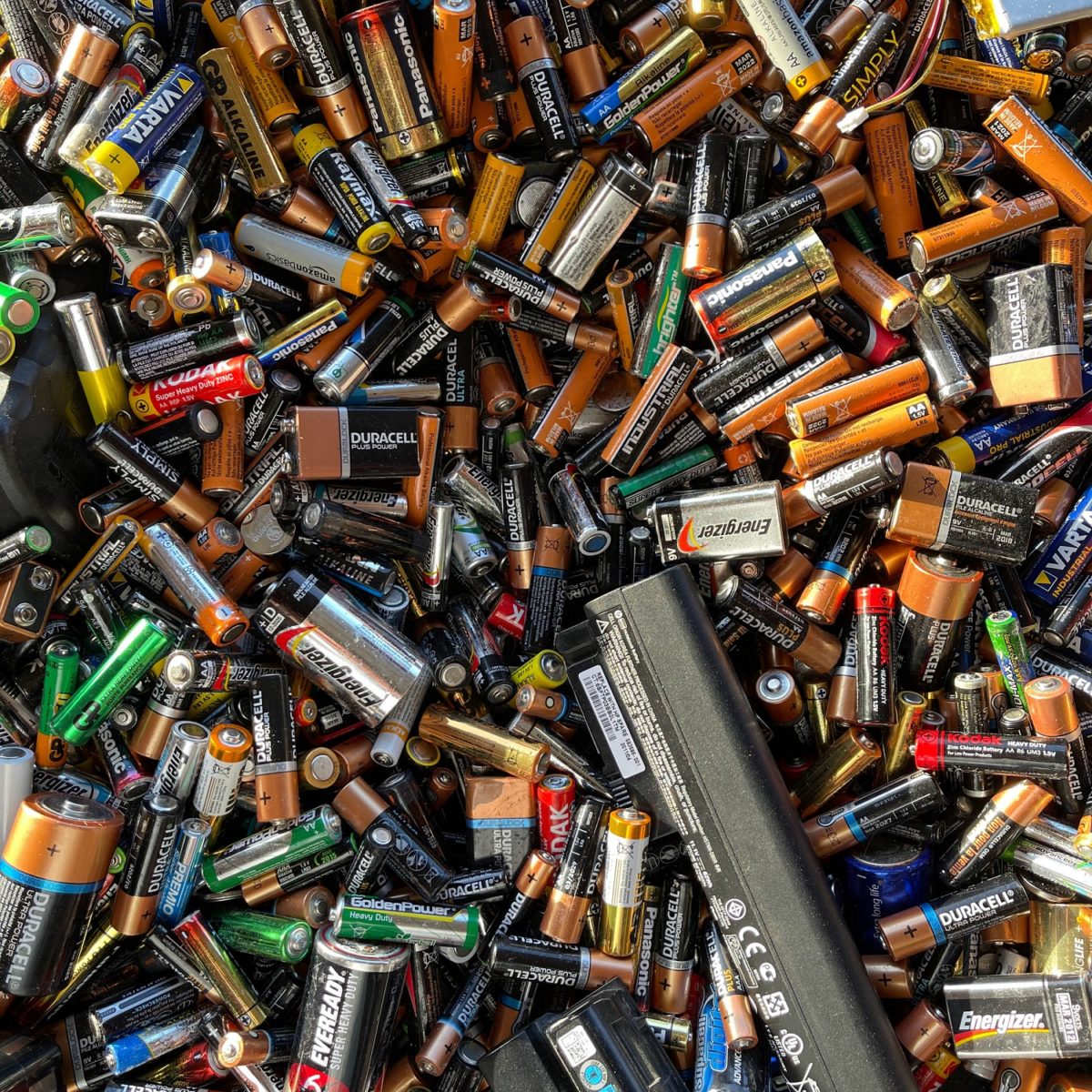 A large pile of used batteries, including brands like Duracell, Energizer, and Panasonic.