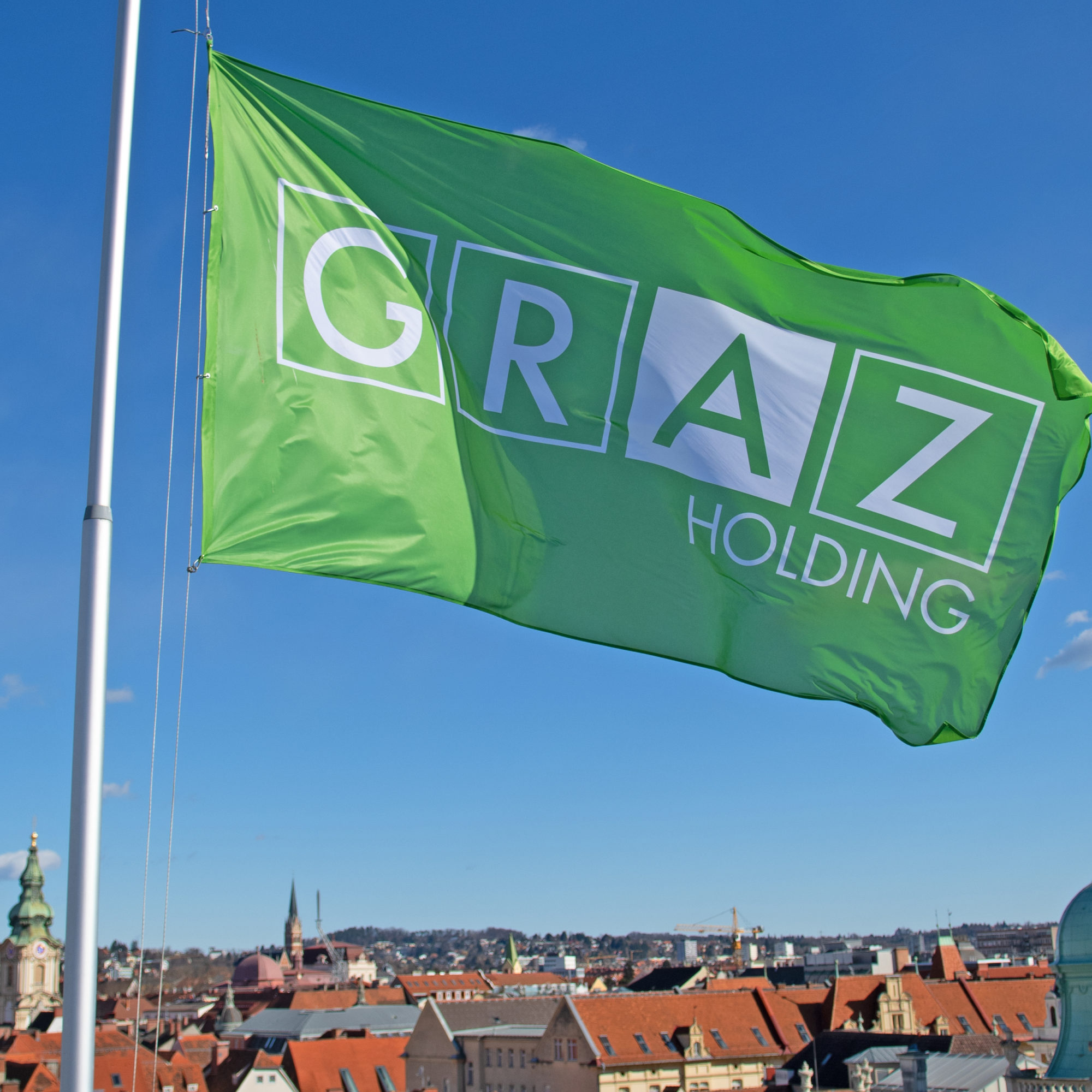 Grüne Fahne im Holding Graz-Design und mit Logo weht auf dem Dach der Holding Graz-Zentrale