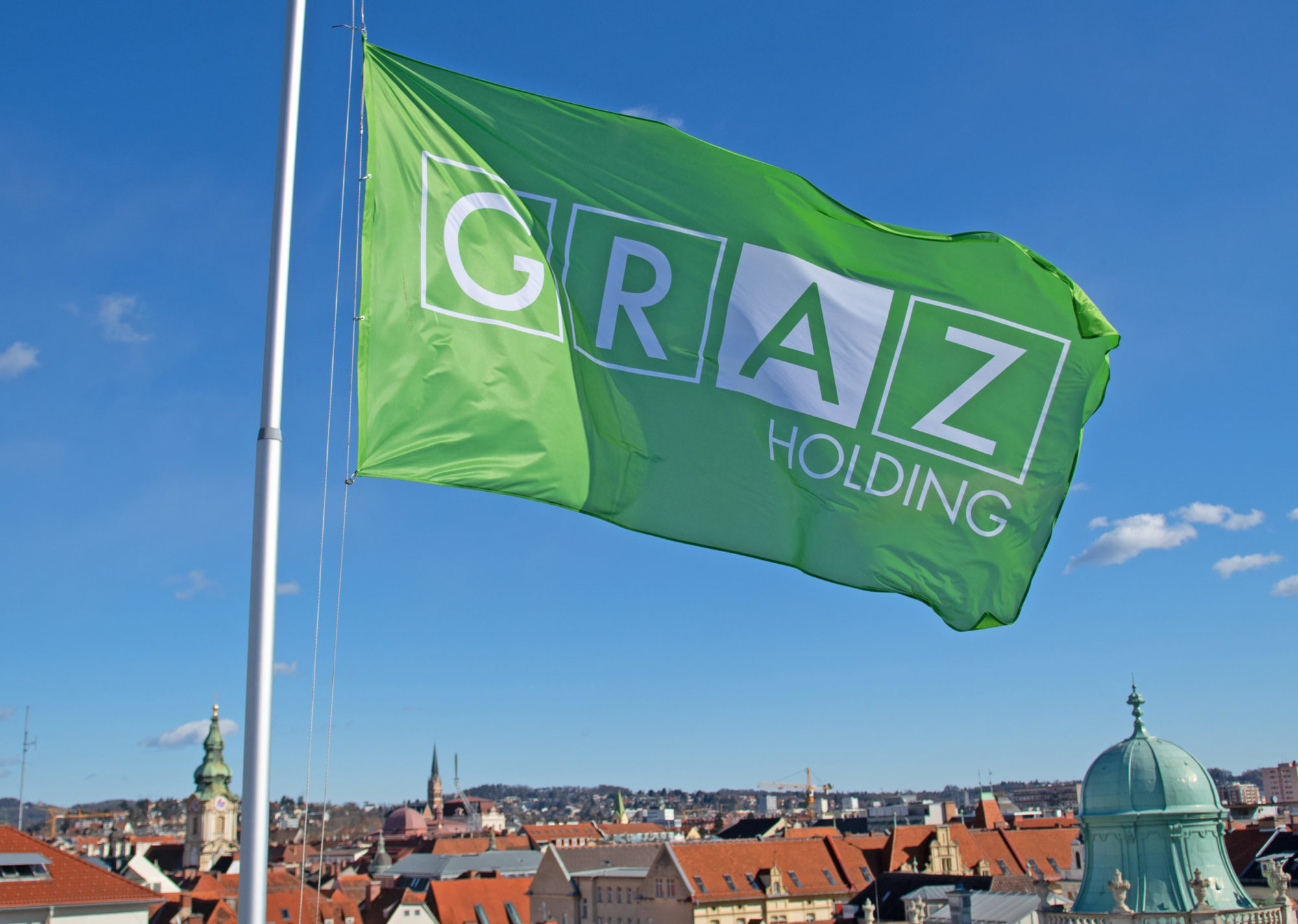 Grüne Fahne im Holding Graz-Design und mit Logo weht auf dem Dach der Holding Graz-Zentrale