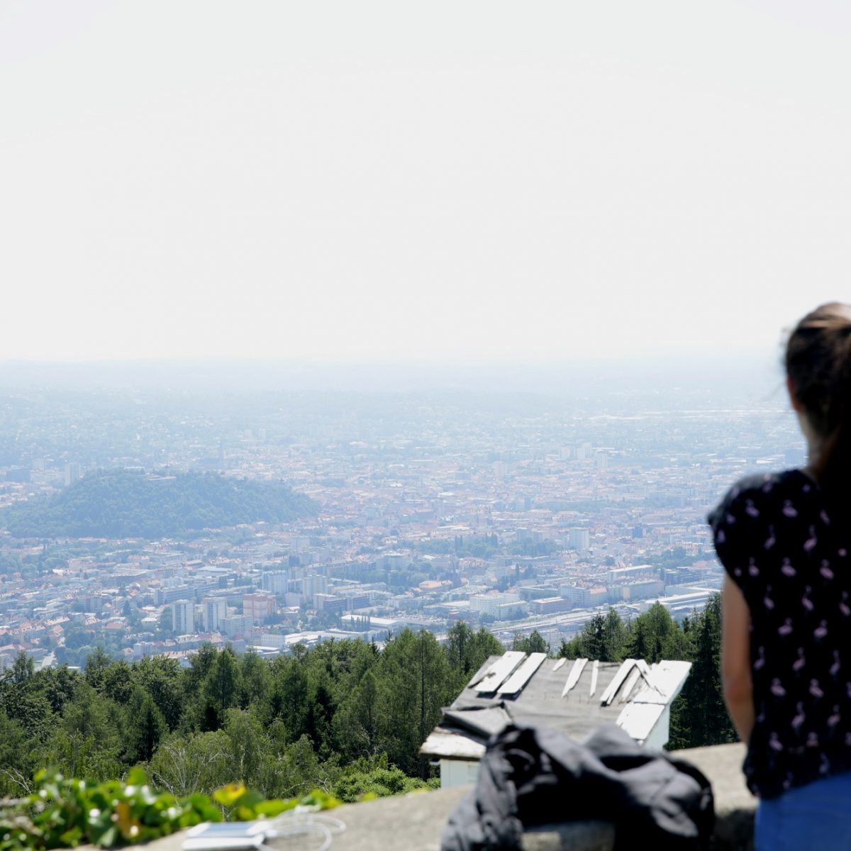 A woman stands on a hilltop overlooking the city of Graz, Austria.