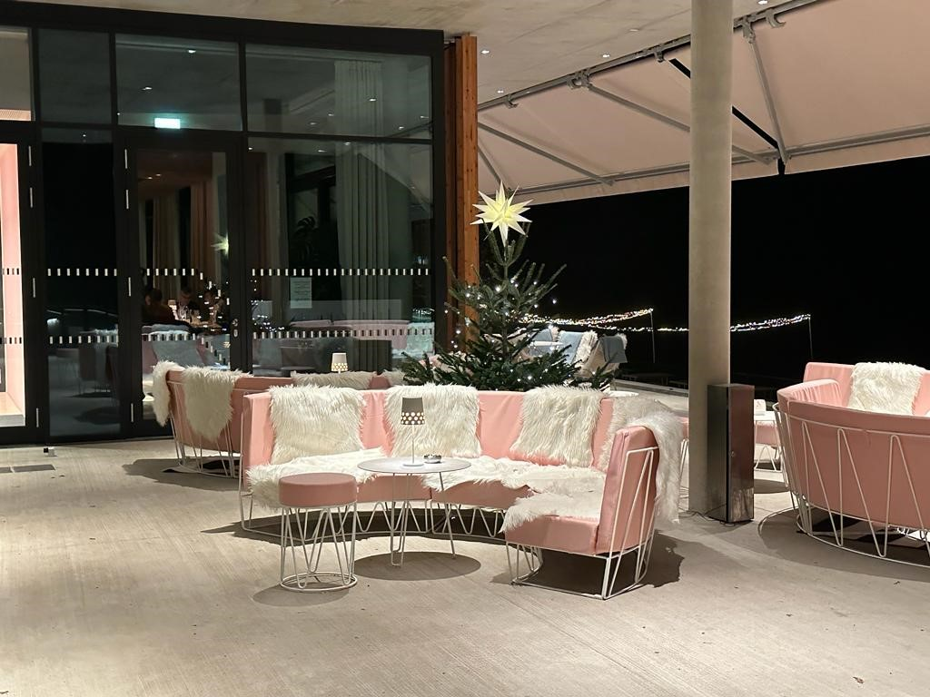 Gemütliche Sitzgruppe mit Fellüberzügen auf Terrasse, dekoriert mit Weihnachtsbaum und Beleuchtung.