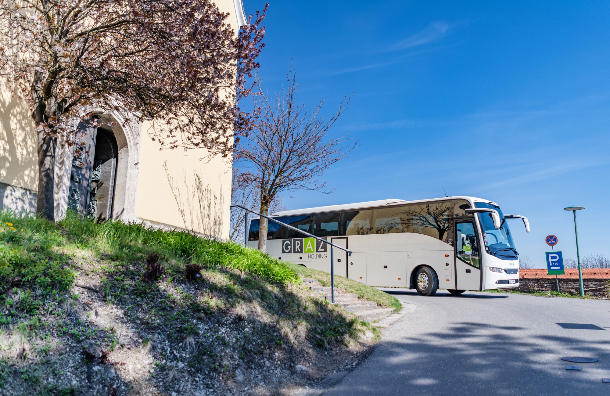 Reisebus der Graz Linien mit Logo der Holding Graz fährt um Kurve bei Schloss St. Martin