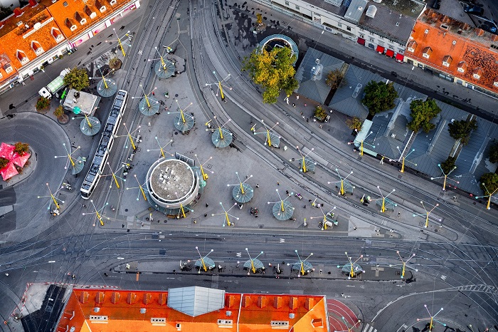 Luftaufnahme des Jakominiplatzes in Graz mit Straßenbahnen, Haltestellen und umliegenden Gebäuden.