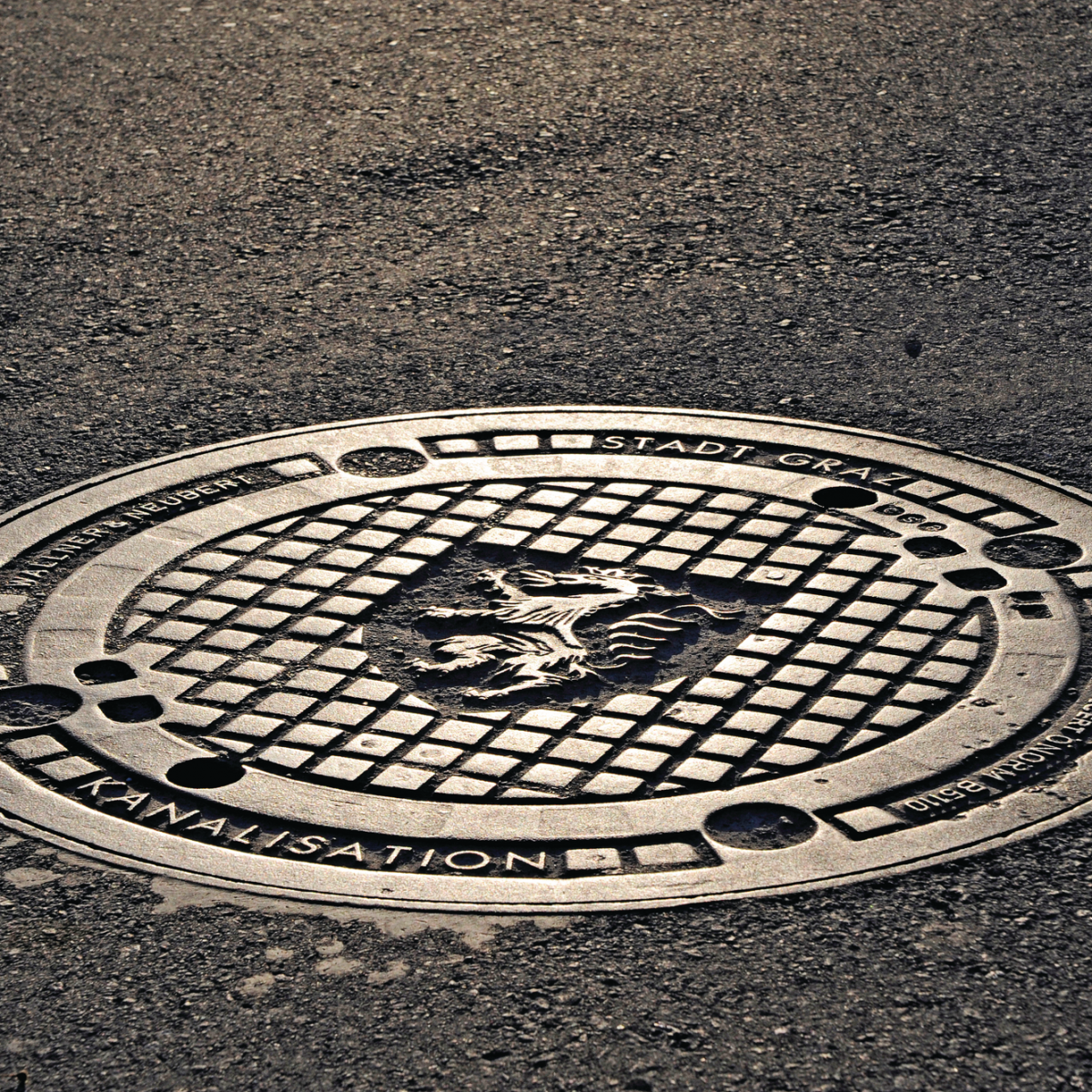 A manhole cover in Graz, Austria, with the city's coat of arms and the inscription "Stadt Graz" (City of Graz).