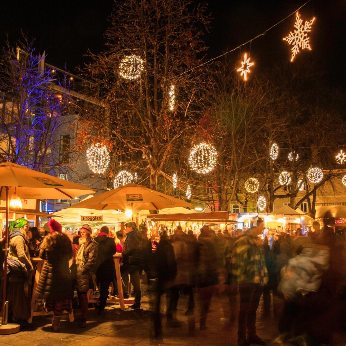 Weihnachtsmarkt Färberplatz mit Menschen, beleuchteten Ständen, Lichterketten und Dekos bei Nacht.