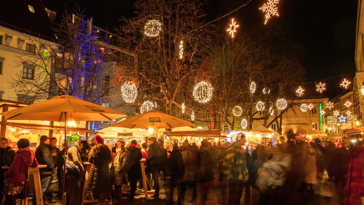 Weihnachtsmarkt Färberplatz mit Menschen, beleuchteten Ständen, Lichterketten und Dekos bei Nacht.