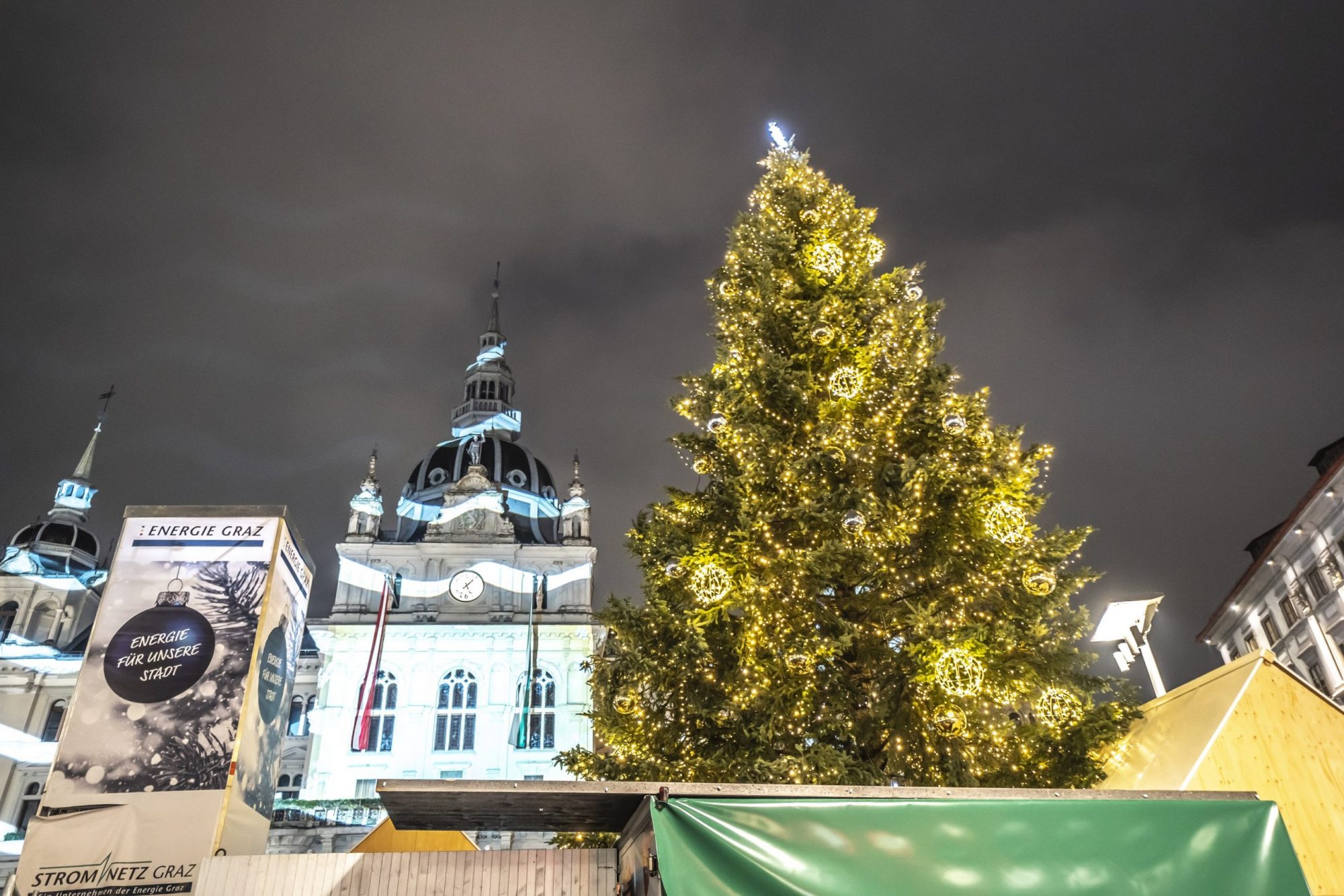 Beleuchteter Weihnachtsbaum auf dem Hauptplatz in Graz vor dem Rathaus mit festlicher Projektion.