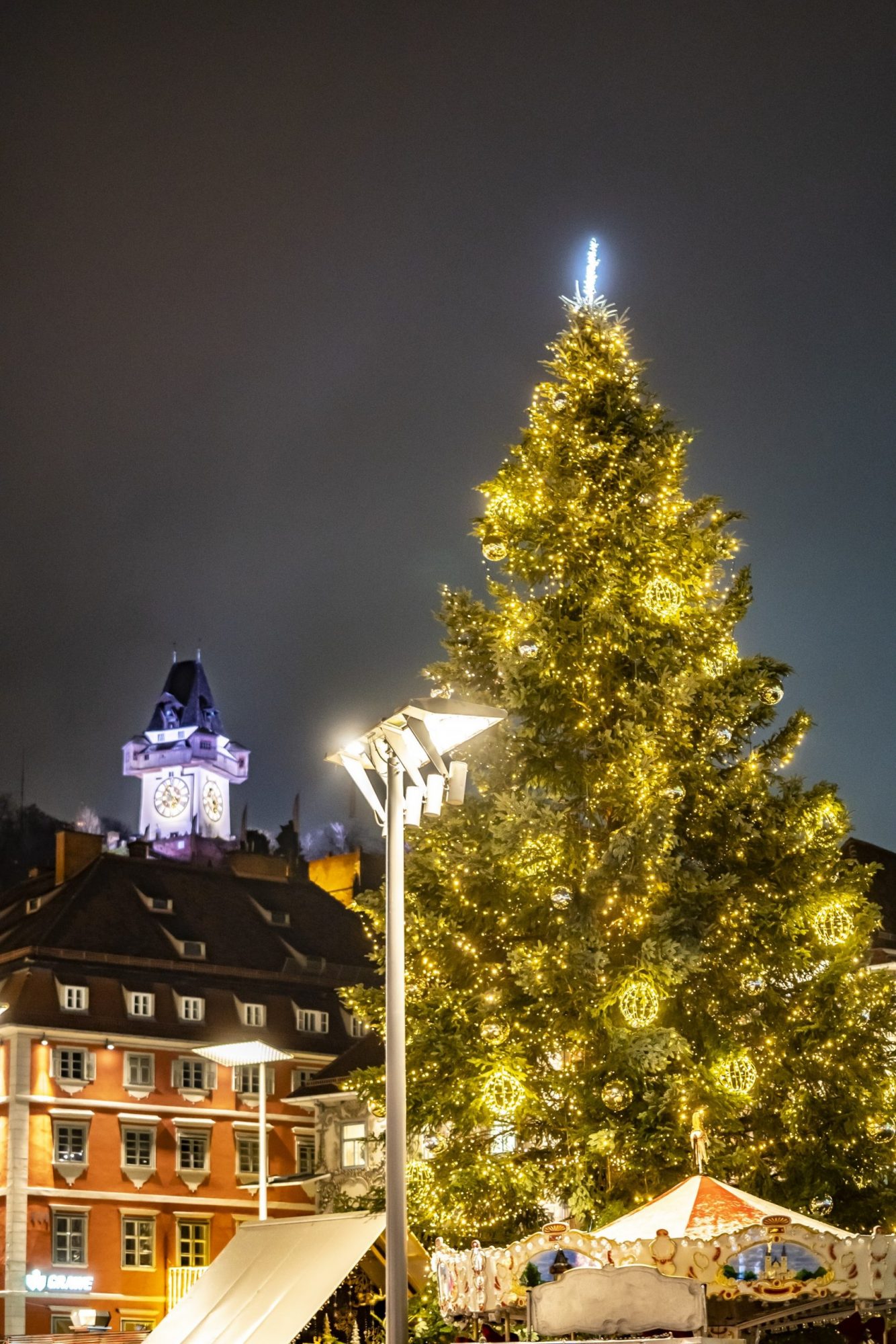 Der hell beleuchtete Weihnachtsbaum am Grazer Hauptplatz, dahinter der Uhrturm.