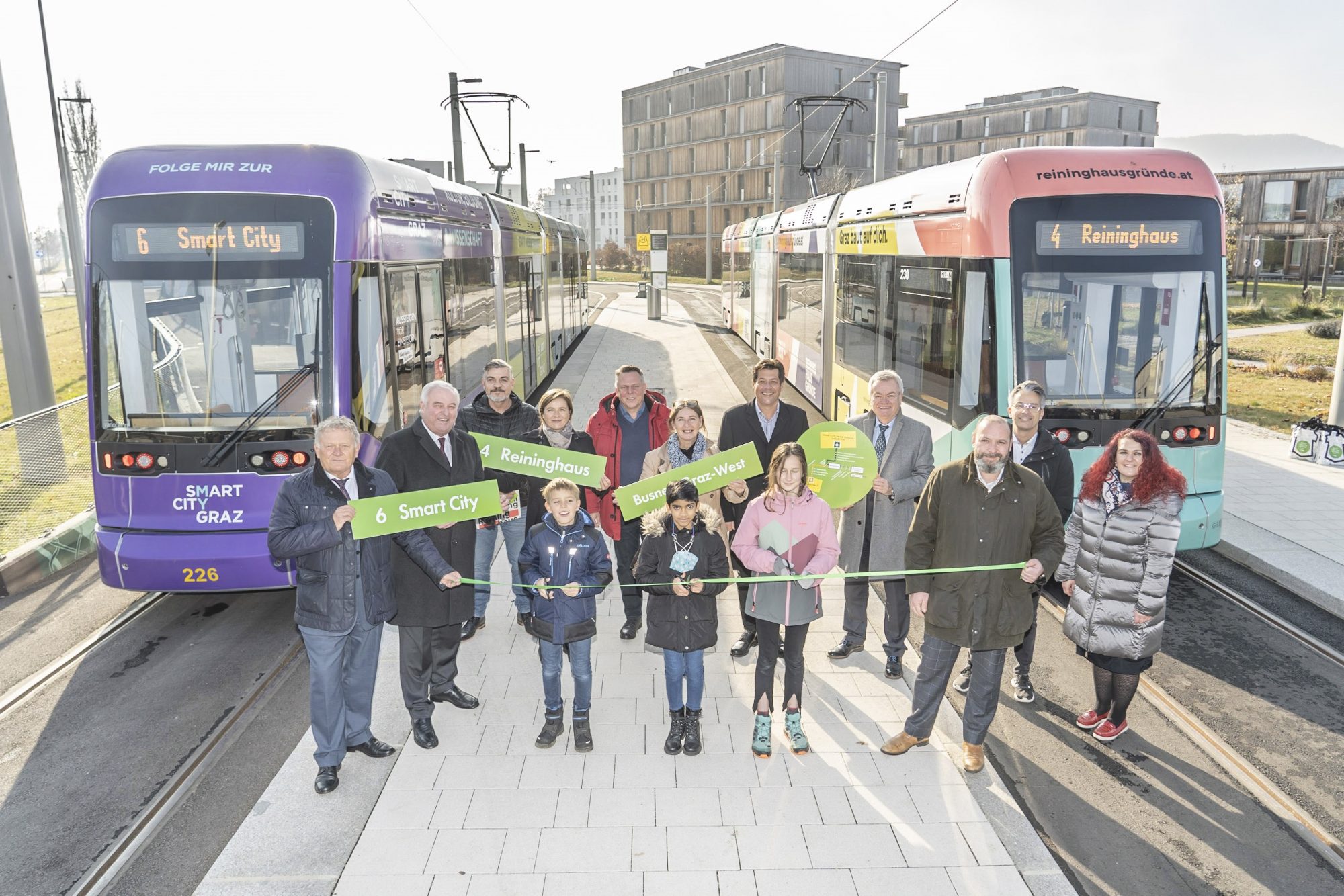 Eröffnung der Straßenbahnverlängerung in Graz mit Menschen, zwei Bahnen und Schildern der Linien 4 und 6.