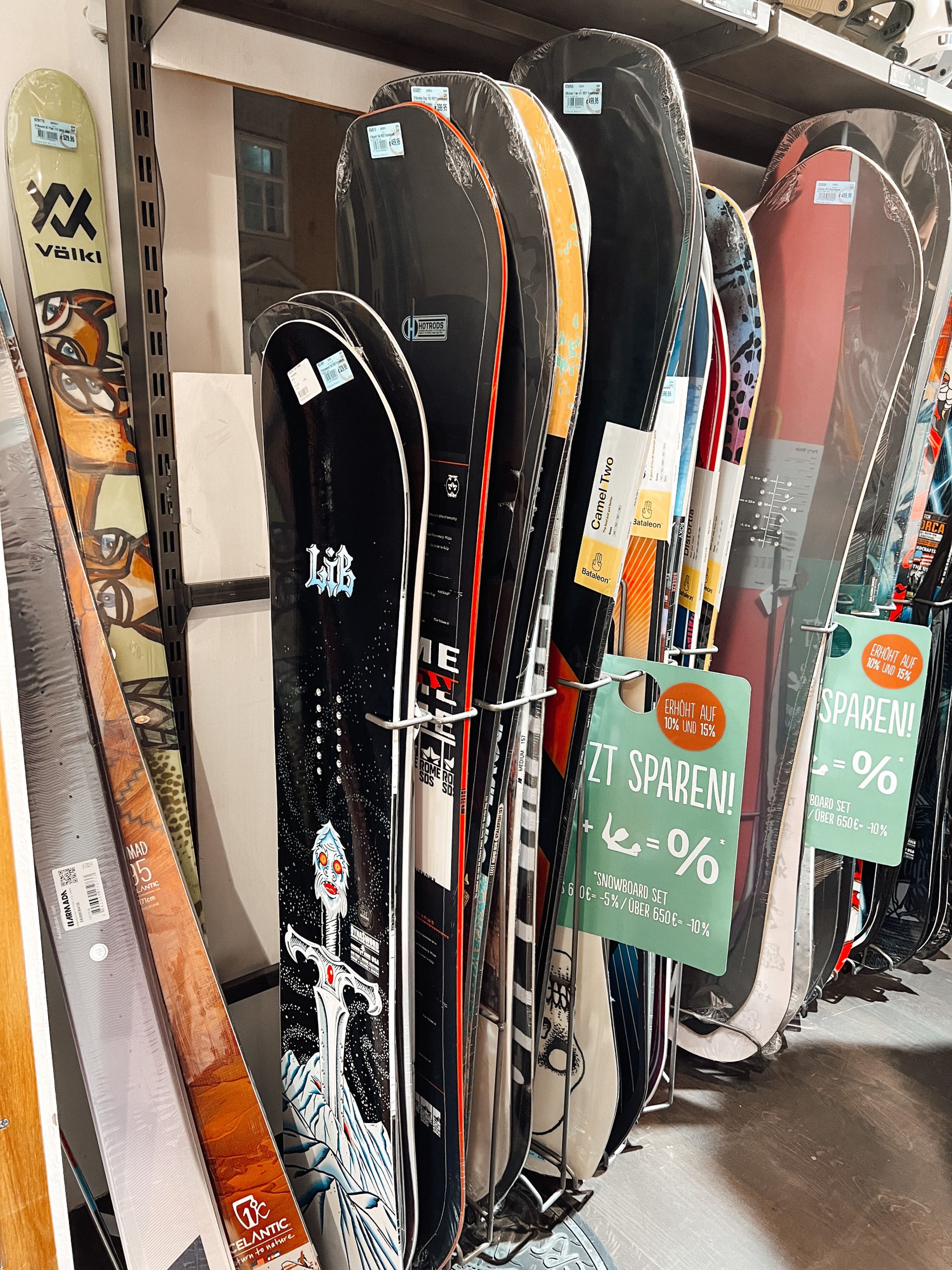 mehrere Snowboards in einer Reihe hintereinander gestapelt an einer Wand in einem Geschäft