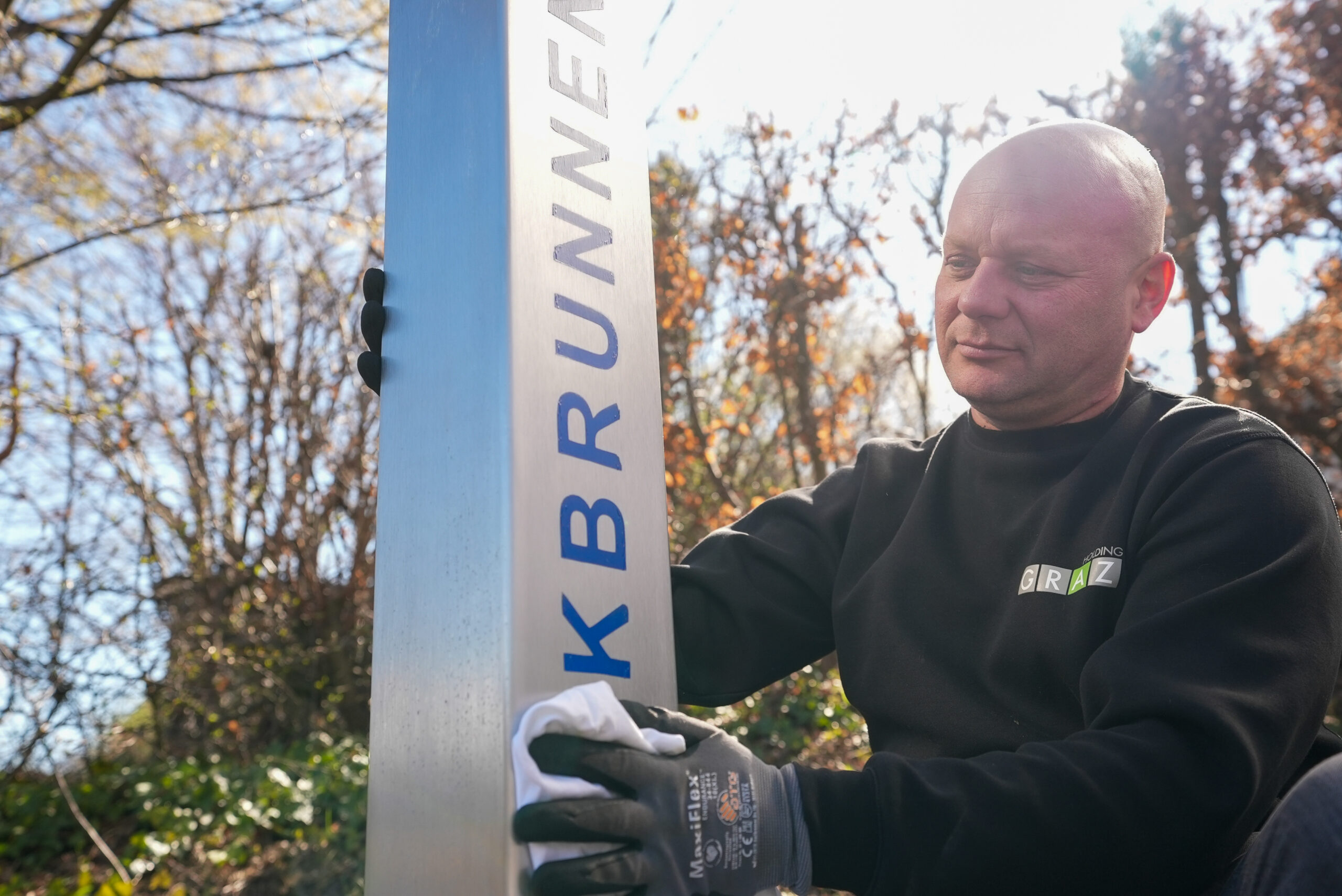 Mitarbeiter der Holding Graz-Wasserwirtschaft in Arbeitskleidung reinigt Trinkbrunnen mit Tuch