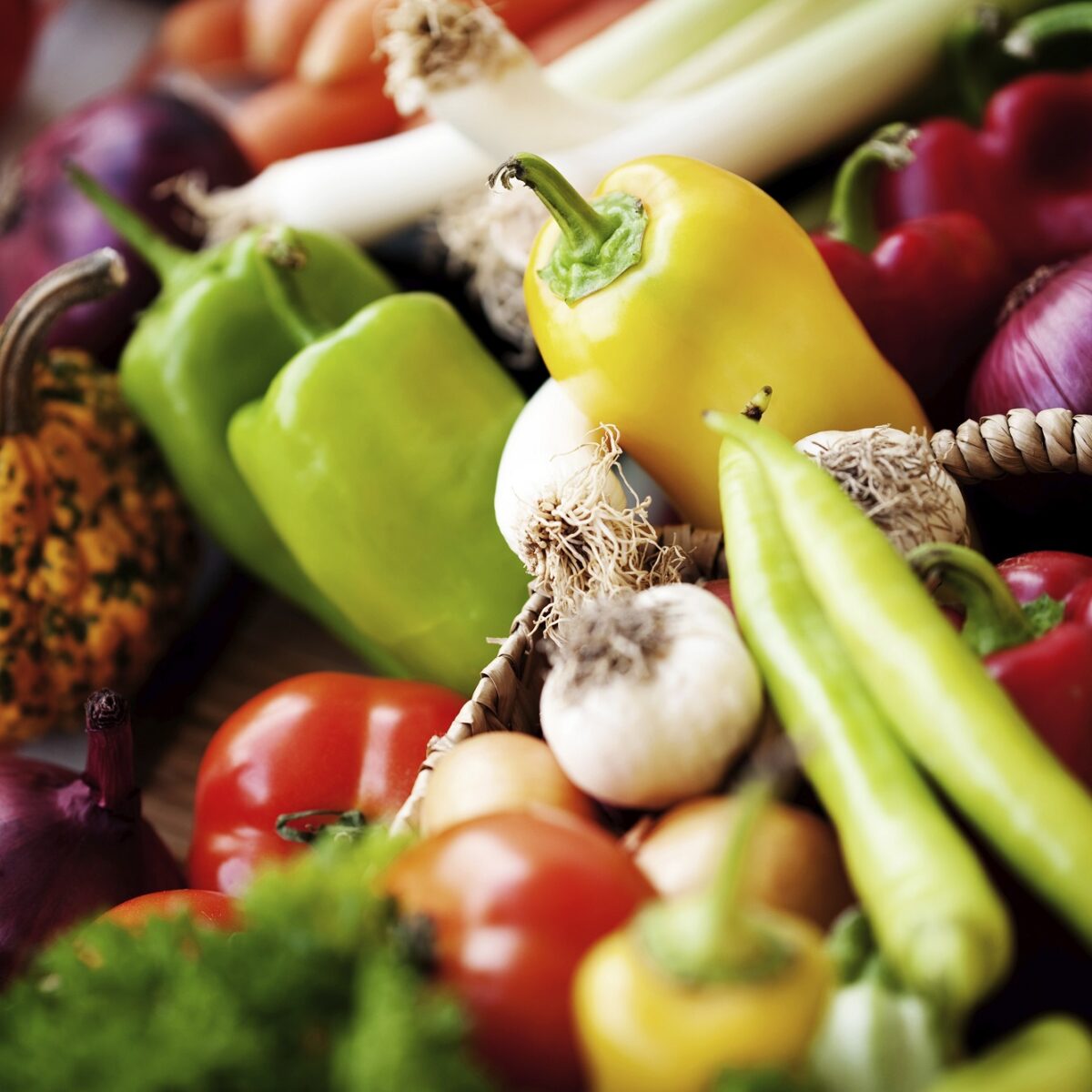 Frisches Gemüse wie Paprika, Karotten, Lauch, Tomaten und Knoblauch in Korb auf einem Marktstand.