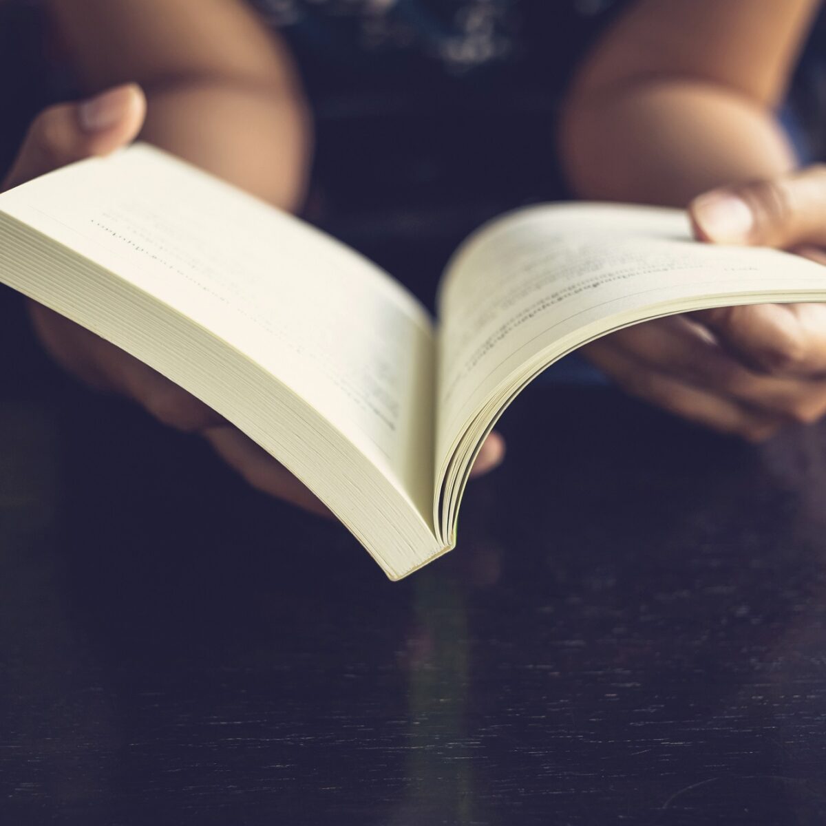 Person hält ein aufgeschlagenes Buch in den Händen, ideal für Lesemomente und Entspannung.